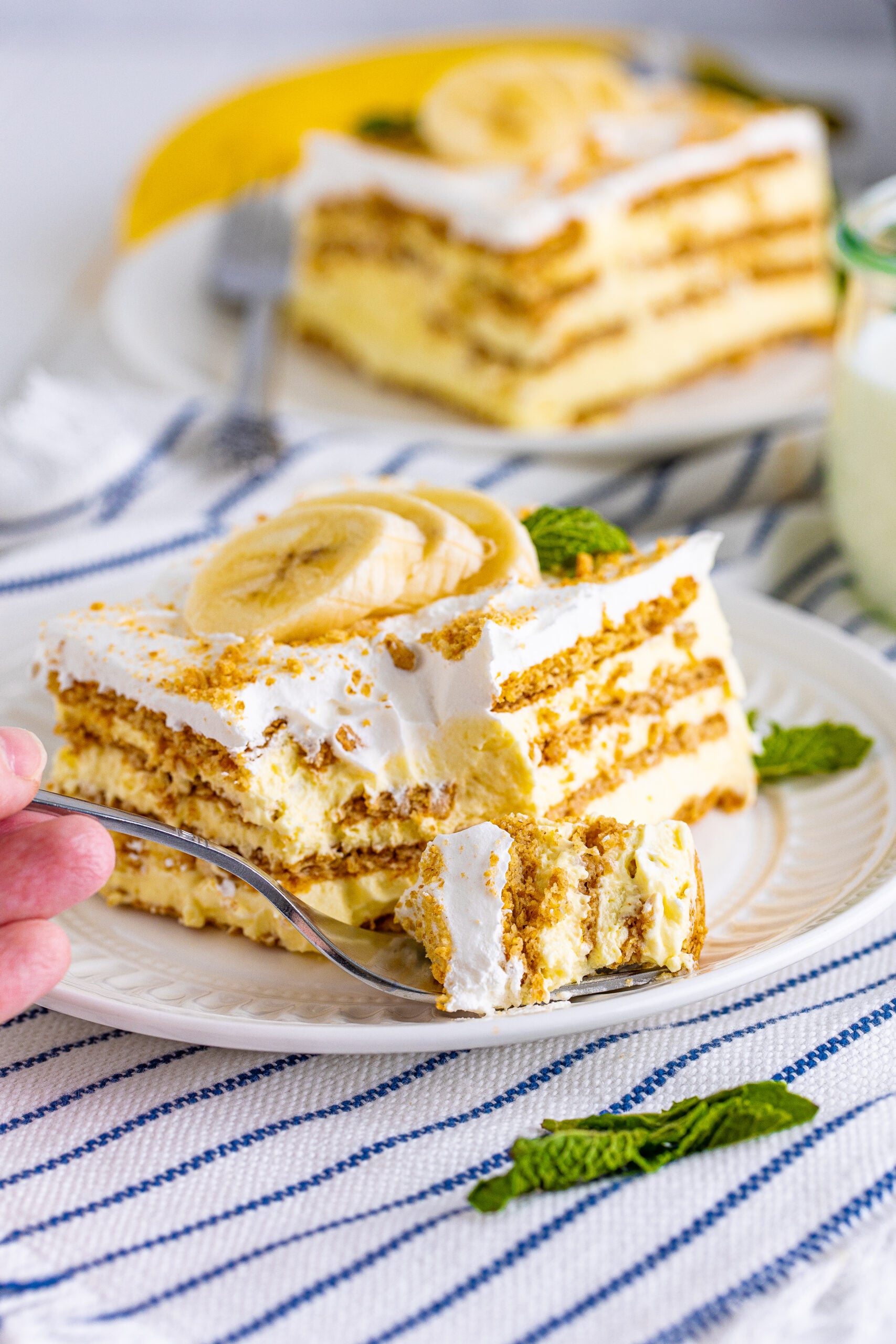 Front view of a slice of Banana Icebox Cake on a white plate with a bite removed by a silver fork.