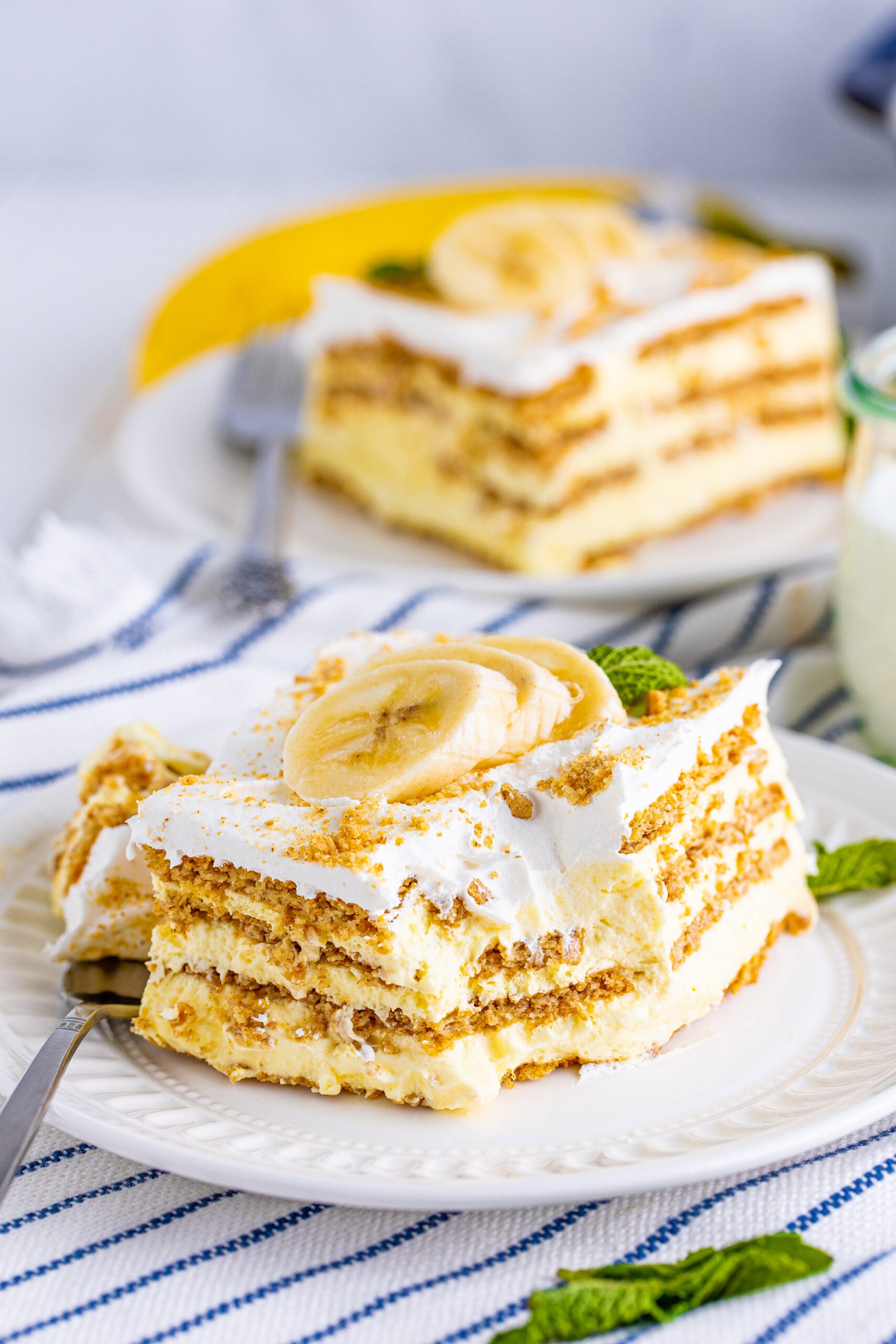 Front view of a slice of Banana Icebox Cake on a white plate with a bite removed by a silver fork.