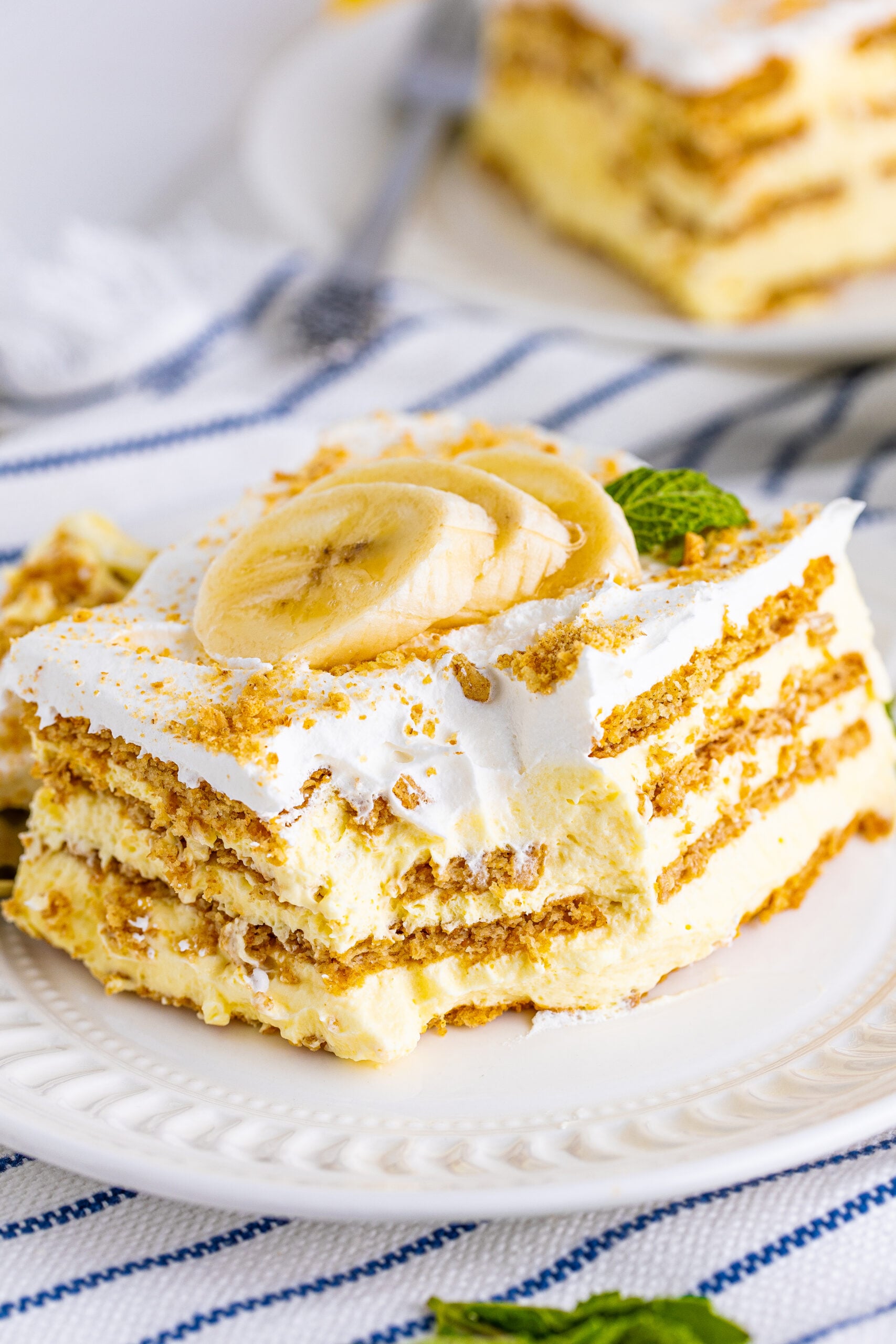Front view of a slice of Banana Icebox Cake on a white plate with a bite removed by a silver fork.
