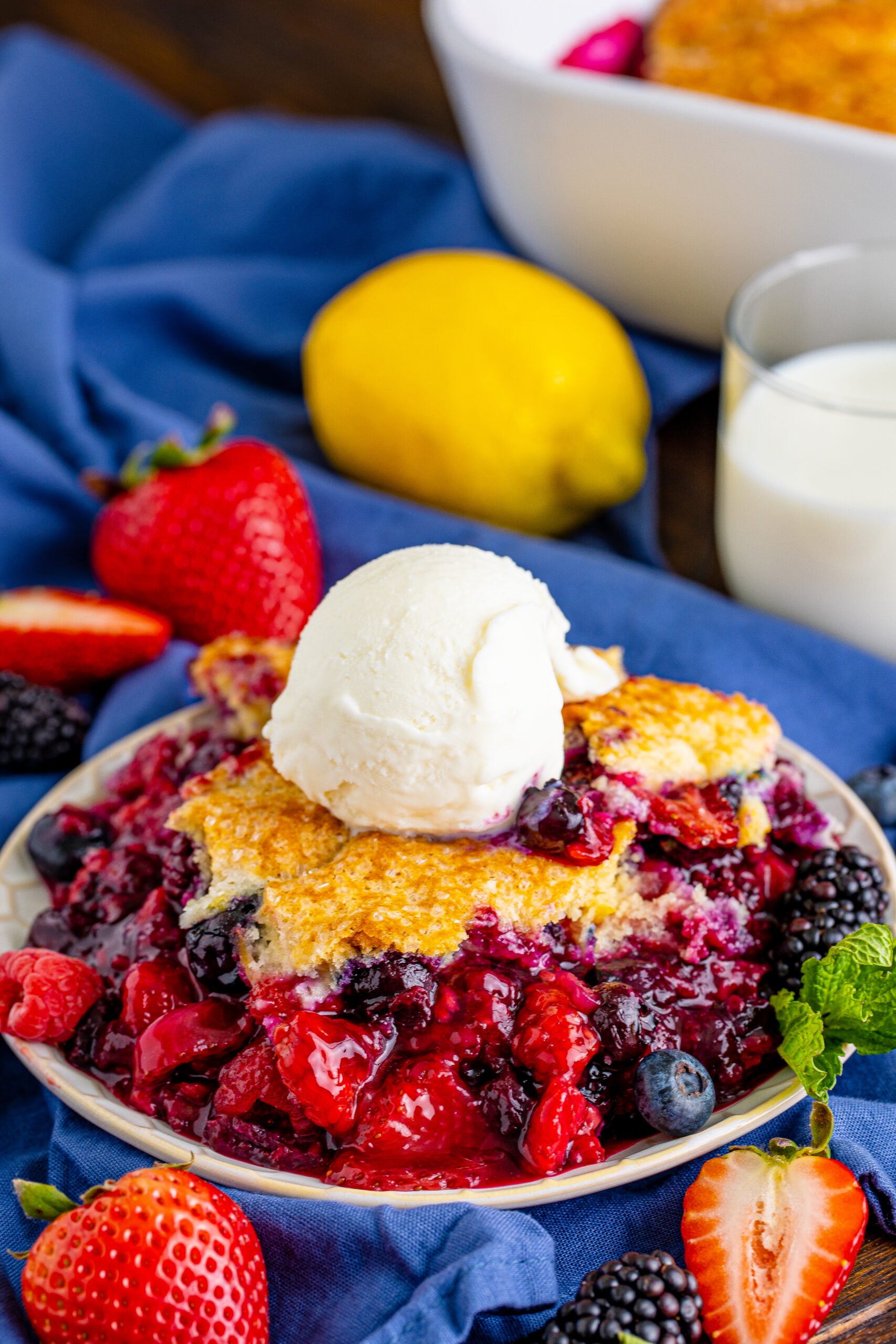 Front view of Mixed Berry Cobbler on a white dish served with a scoop of vanilla ice cream.