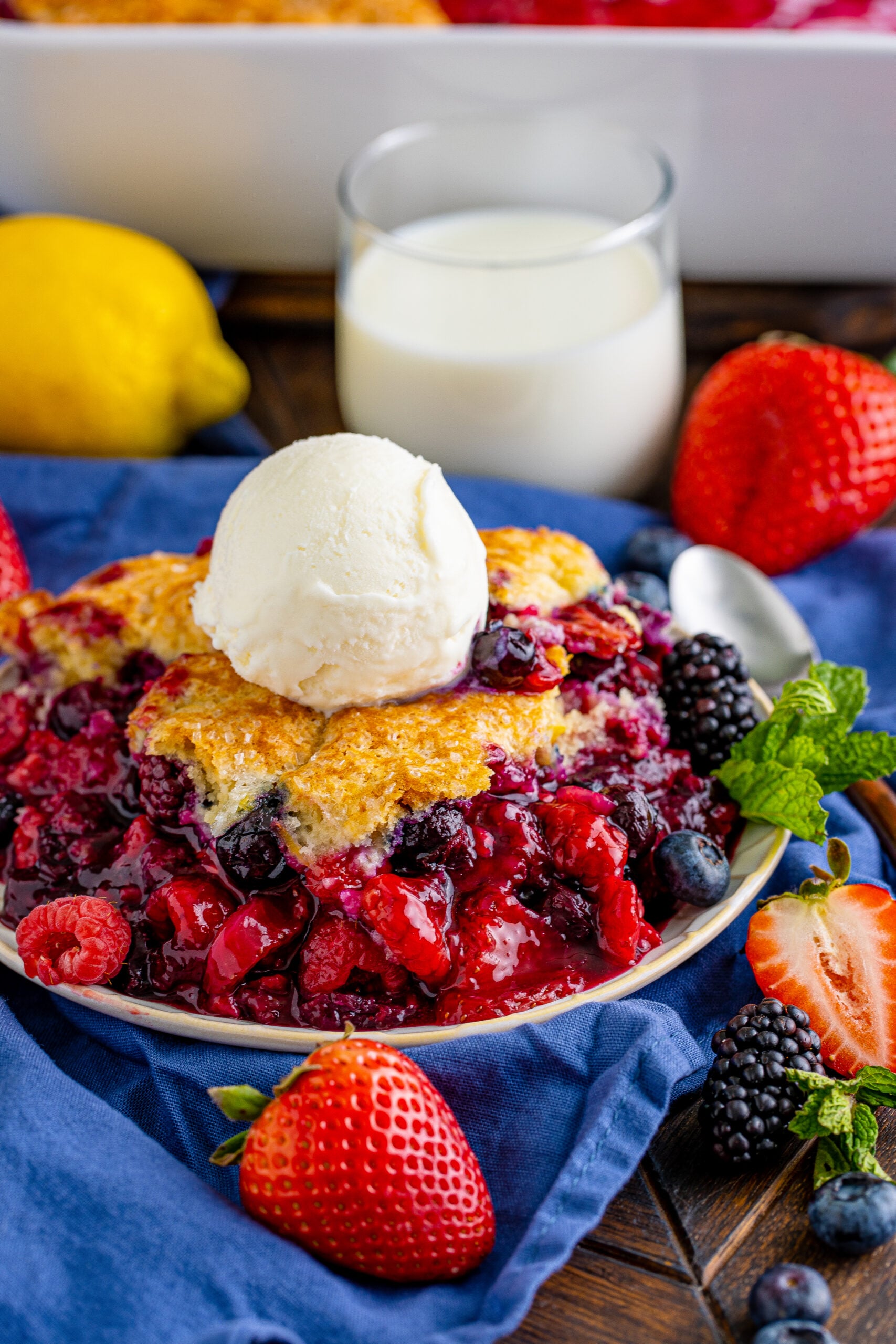 Front view of Mixed Berry Cobbler on a white dish served with a scoop of vanilla ice cream.