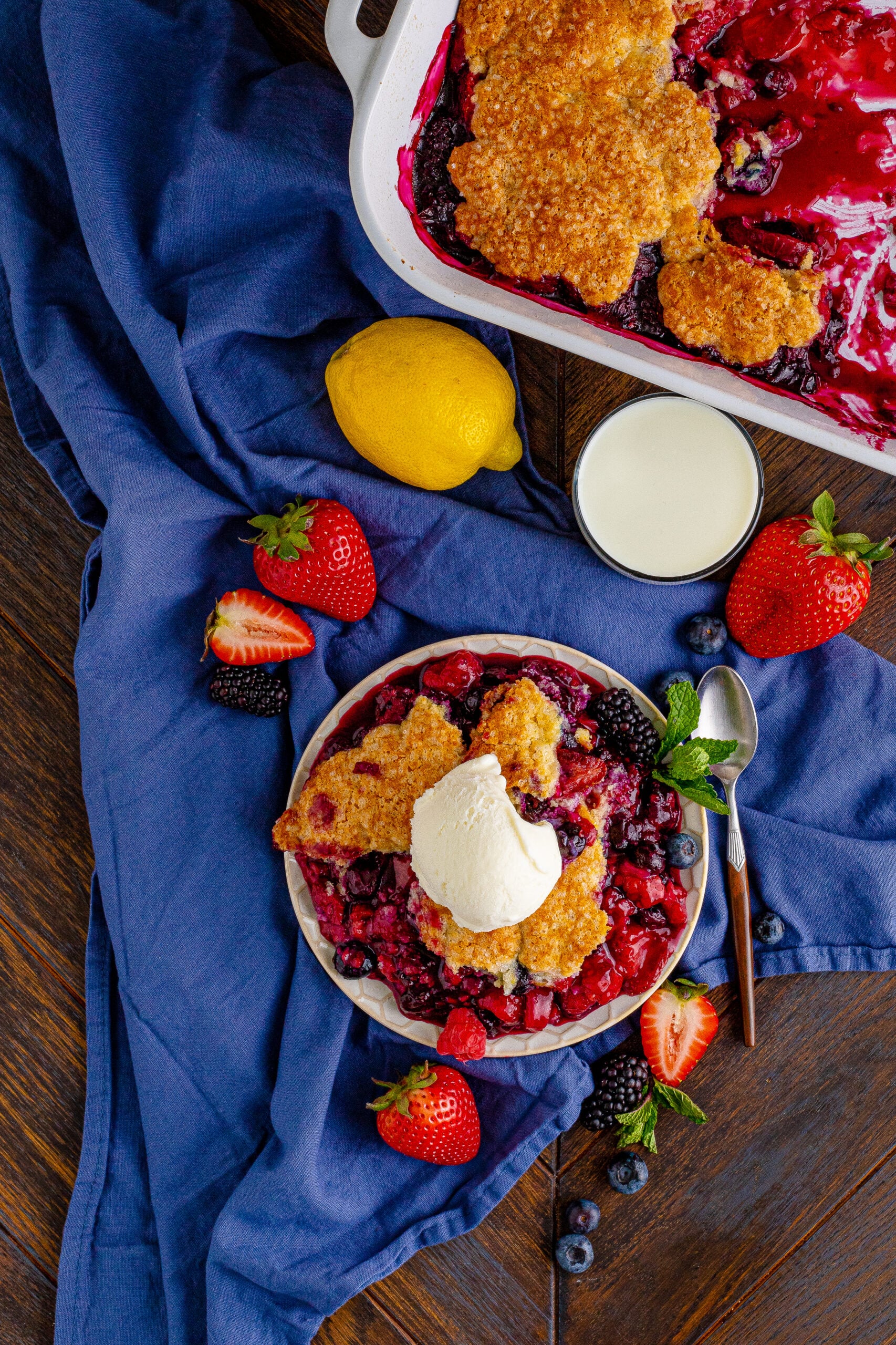 Overhead view of Mixed Berry Cobbler on a white dish served with a scoop of vanilla ice cream.