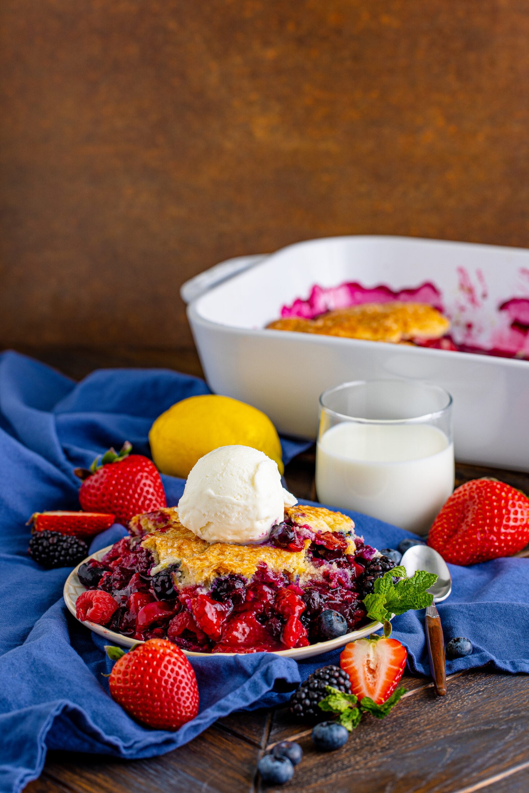 Front view of Mixed Berry Cobbler on a white dish served with a scoop of vanilla ice cream.