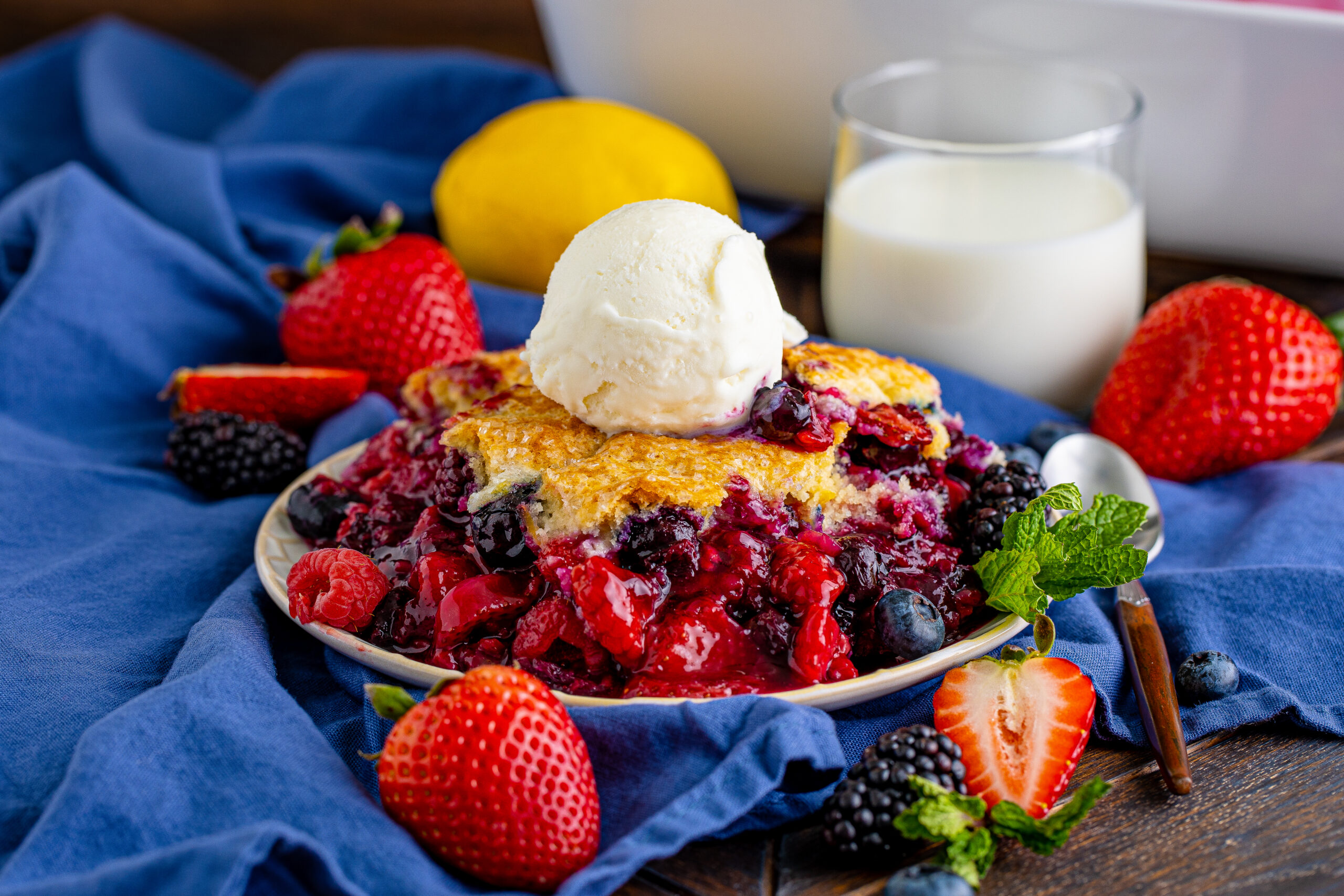 Front view of Mixed Berry Cobbler on a white dish served with a scoop of vanilla ice cream.