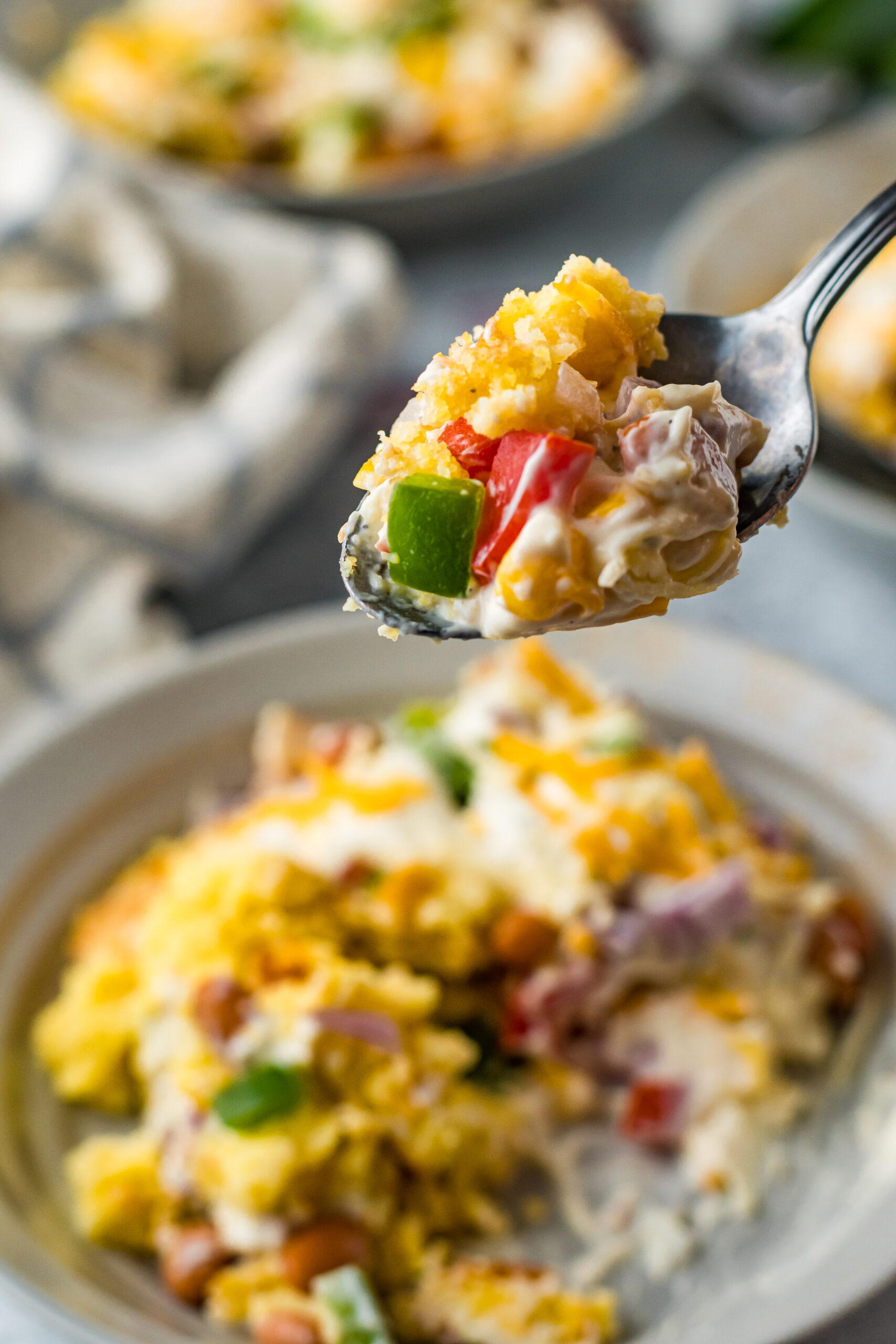 Front view of a bite of Cornbread Salad on a silver spoon.