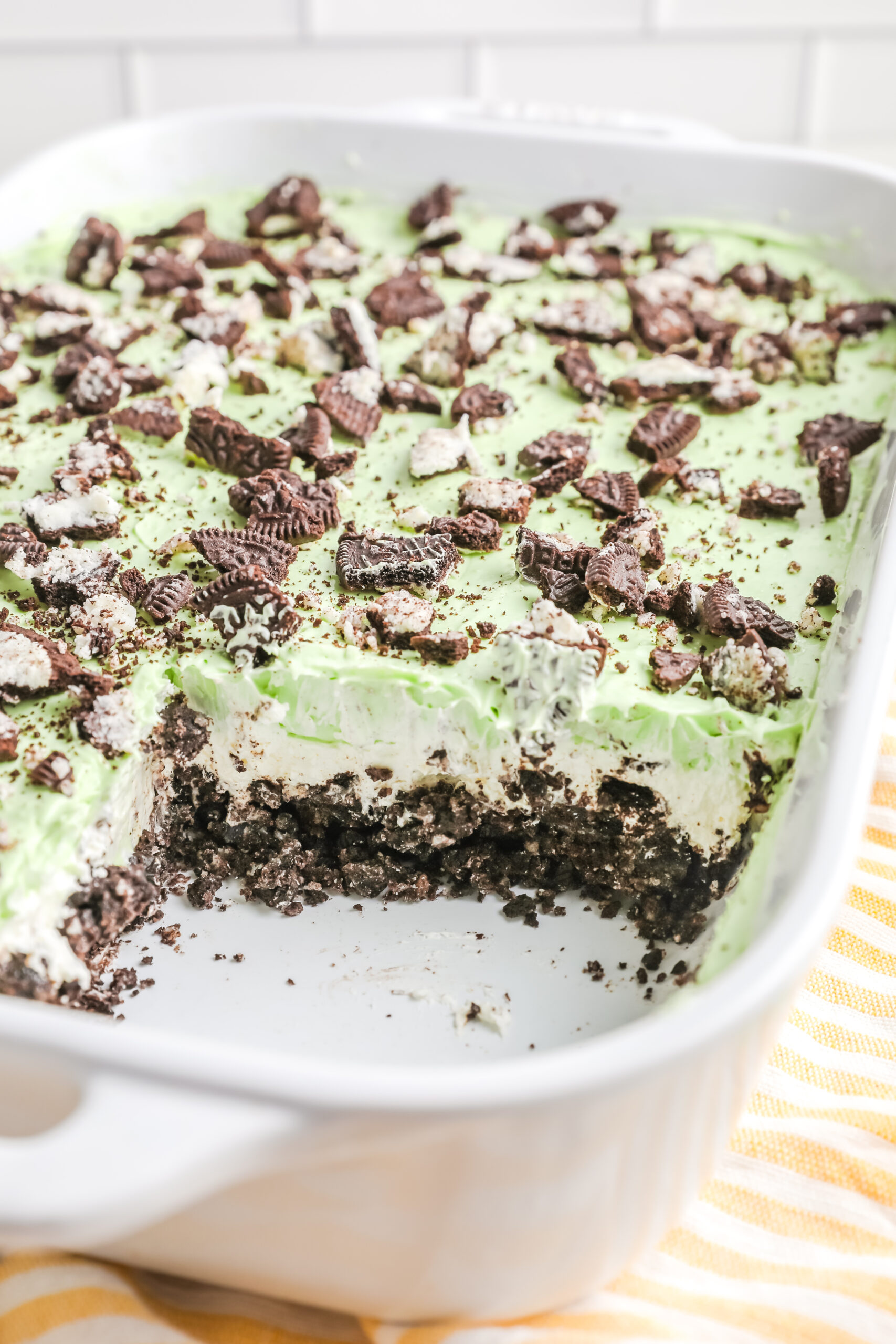 Shamrock Lasagna in a white baking dish with a piece removed showing the different layers.
