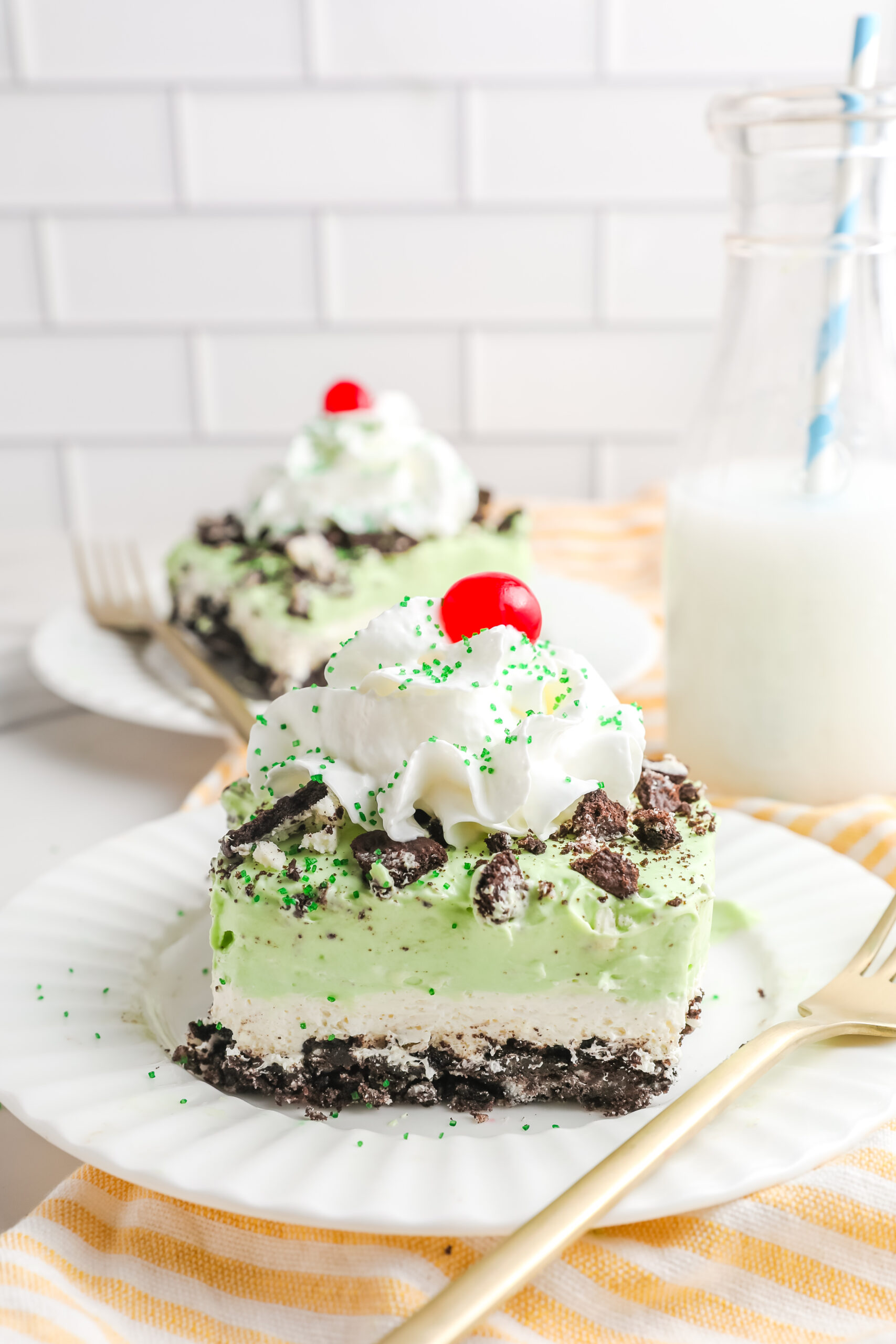 Two pieces of Shamrock Lasagna on white plates with gold forks.