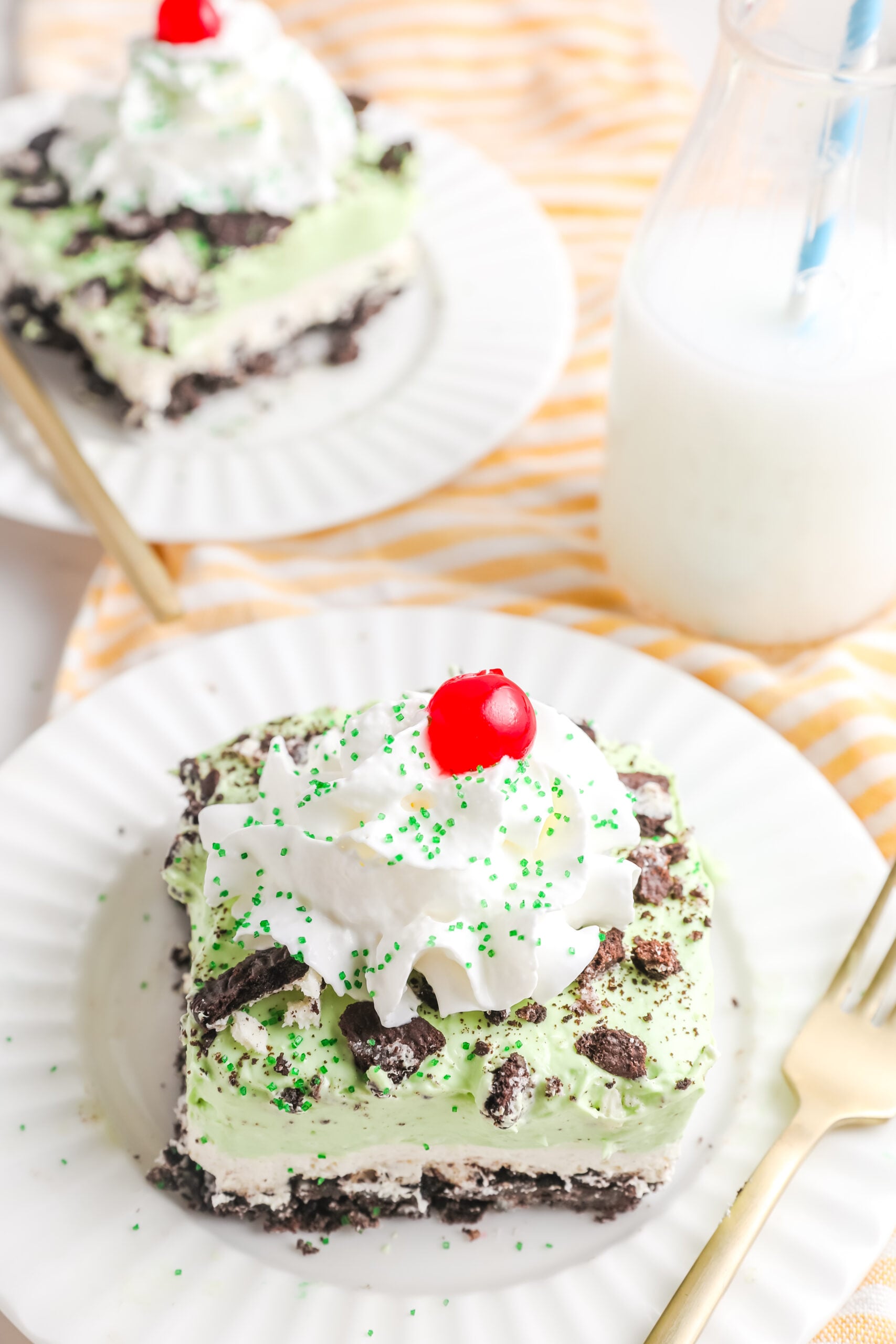 Two pieces of Shamrock Lasagna on white plates with gold forks.