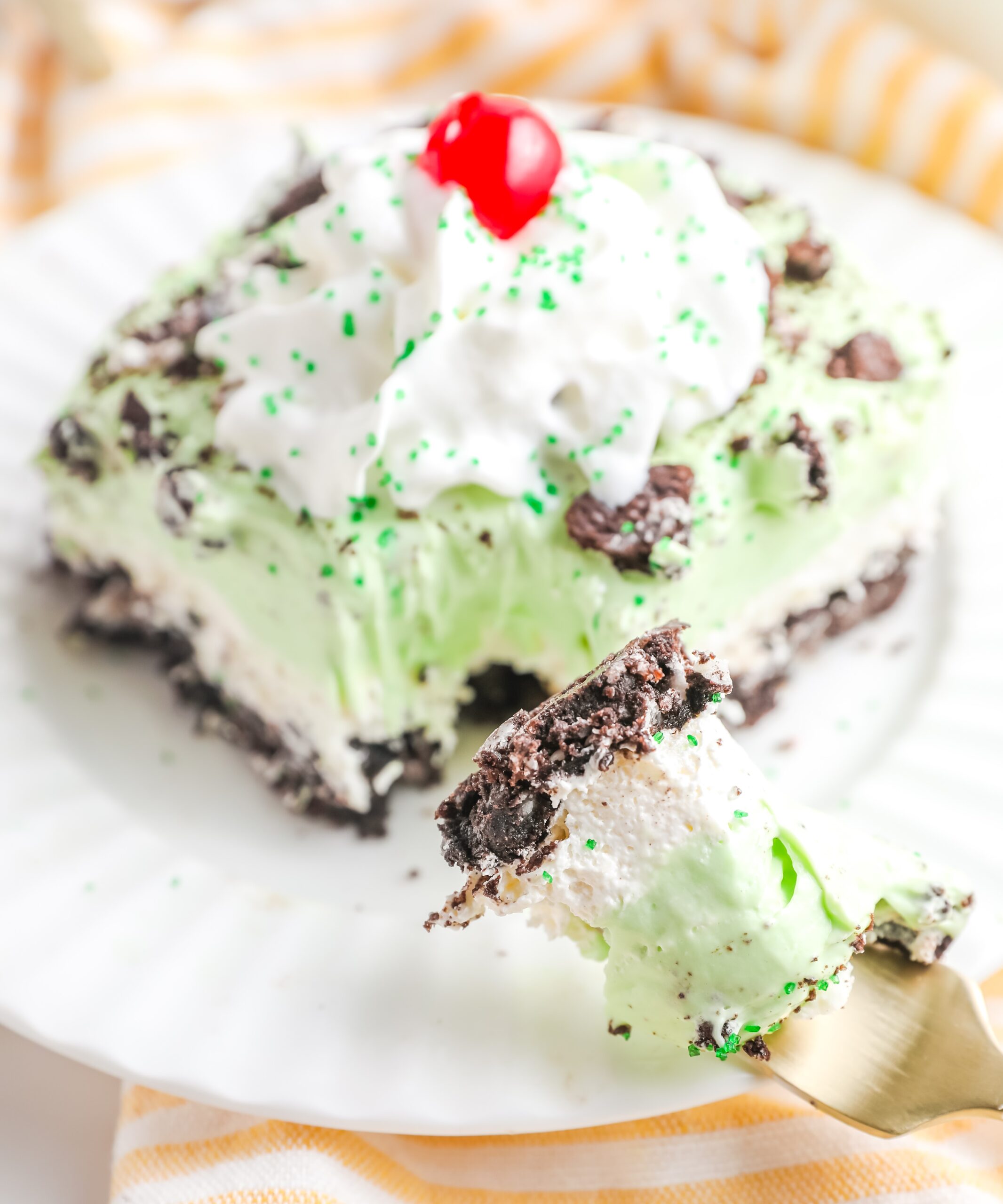 Side angle of the lasagna topped with whipped cream and a cherr.