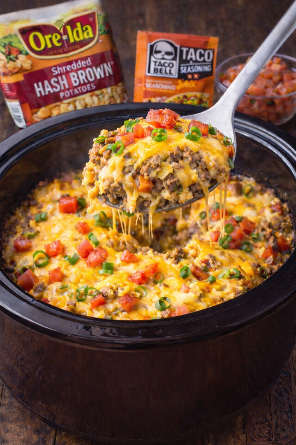 Slow Cooker John Wayne Casserole in a black crockpot with a spoon lifting some up