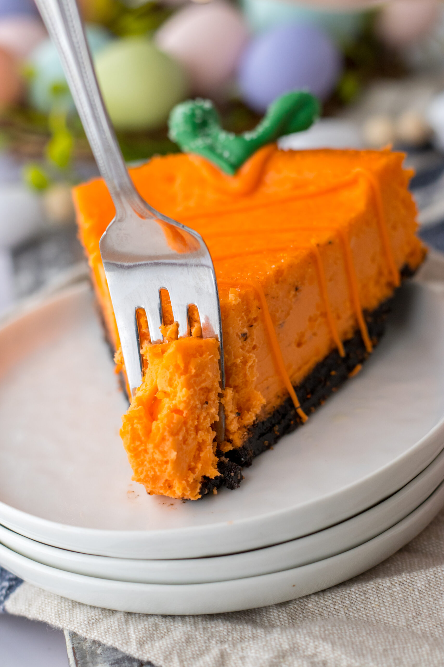 A cheesecake carrot on a white plate with a silver fork removing a bite.