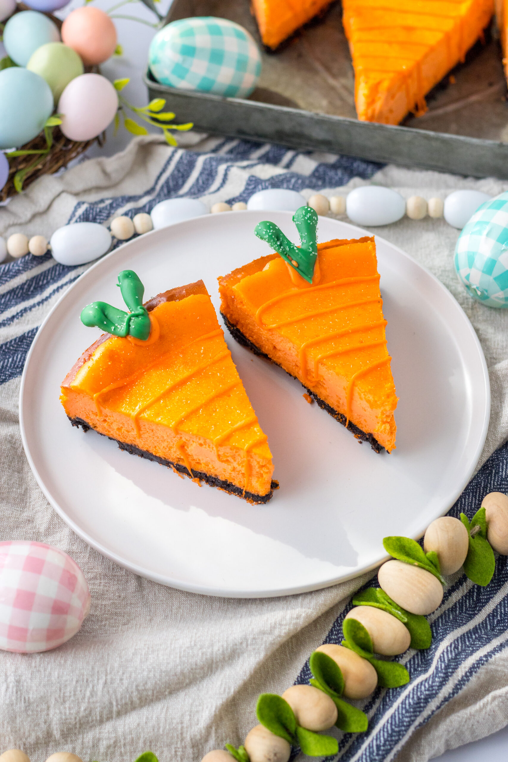 Two Cheesecake Carrots on a white plate with a white and blue linen in the background.