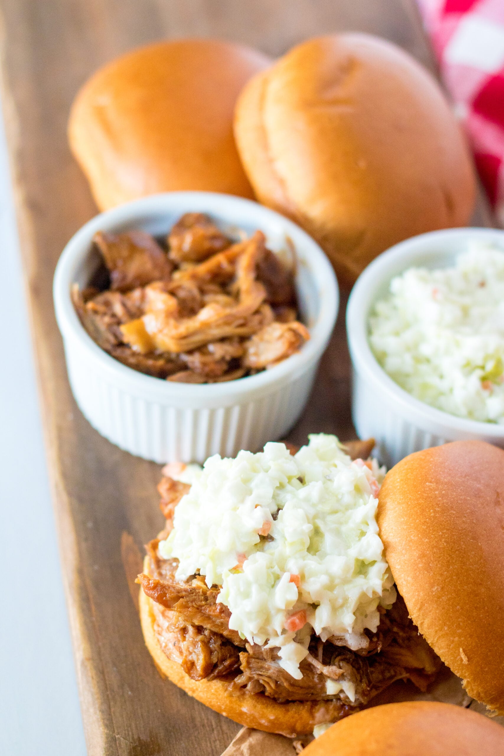 Close up view of Slow Cooker Cola Pulled Pork on a bun served with coleslaw.