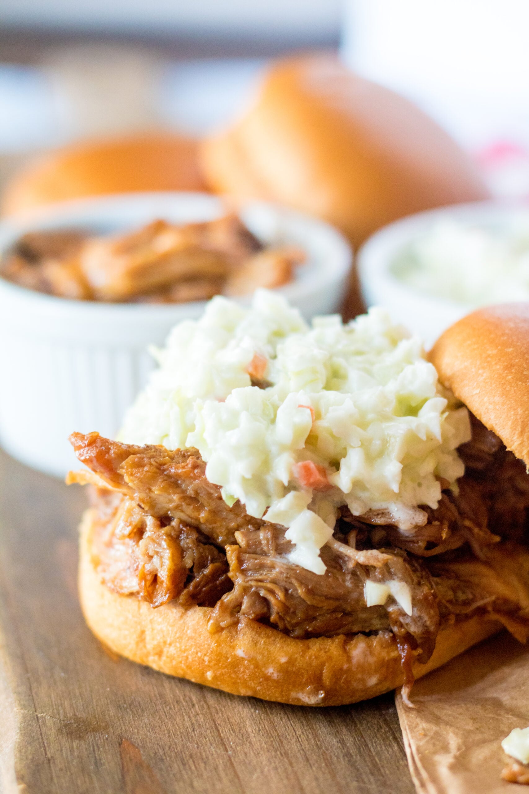 Close up view of Slow Cooker Cola Pulled Pork on a bun served with coleslaw.
