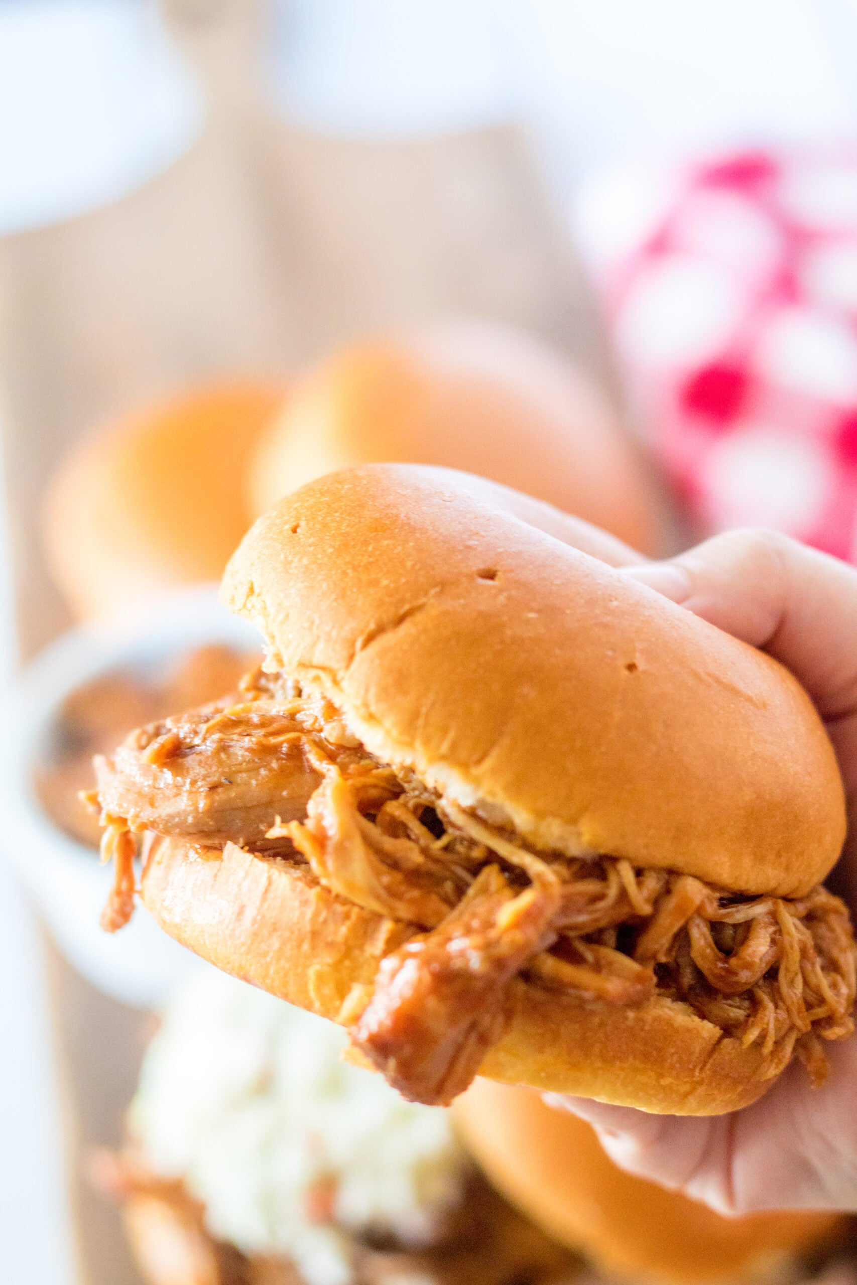 Front view of a Slow Cooker Cola Pulled pork sandwich being held.