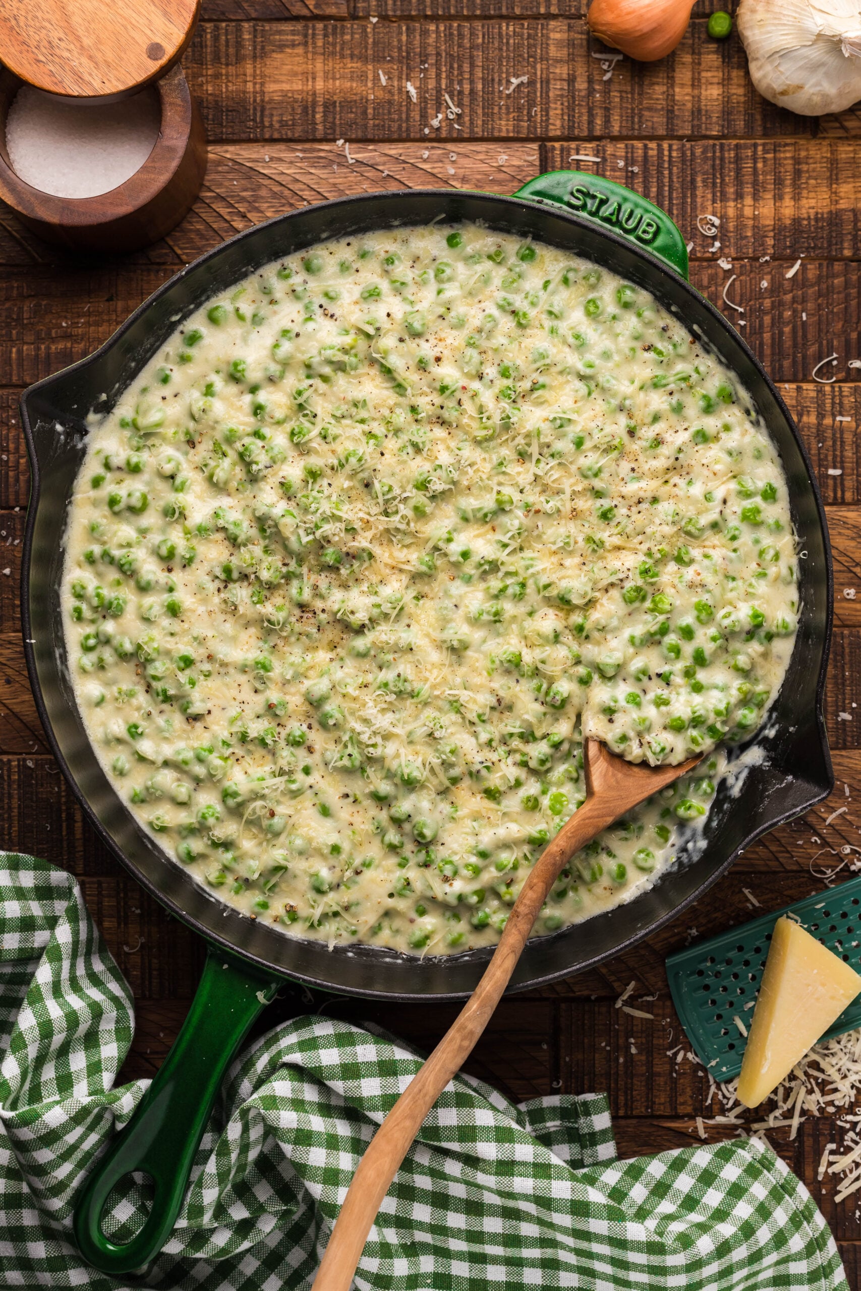 Creamed Peas in a black and green cast iron skillet with a wood spoon. 