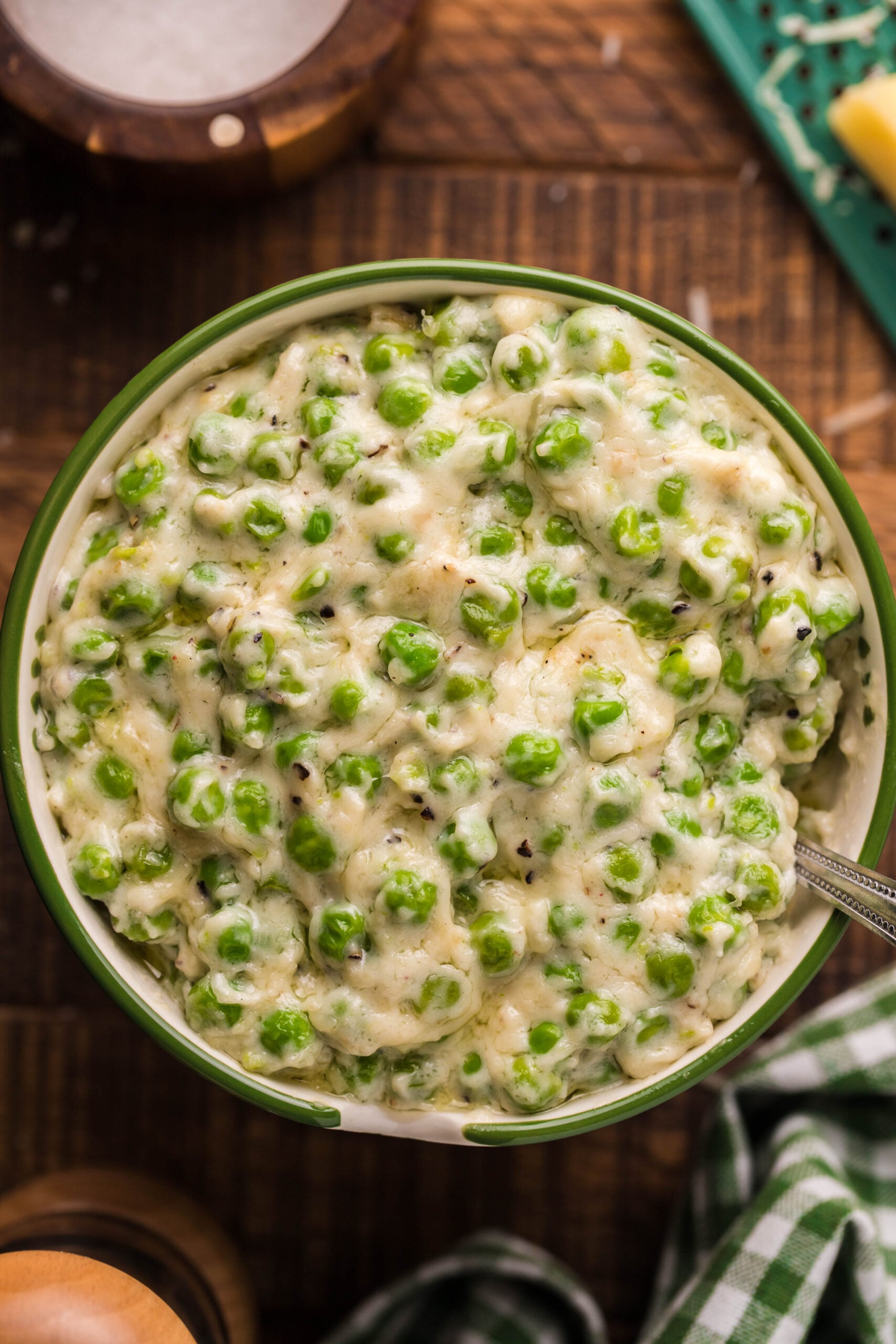 Close up shot of creamed peas in a green and white bowl. 