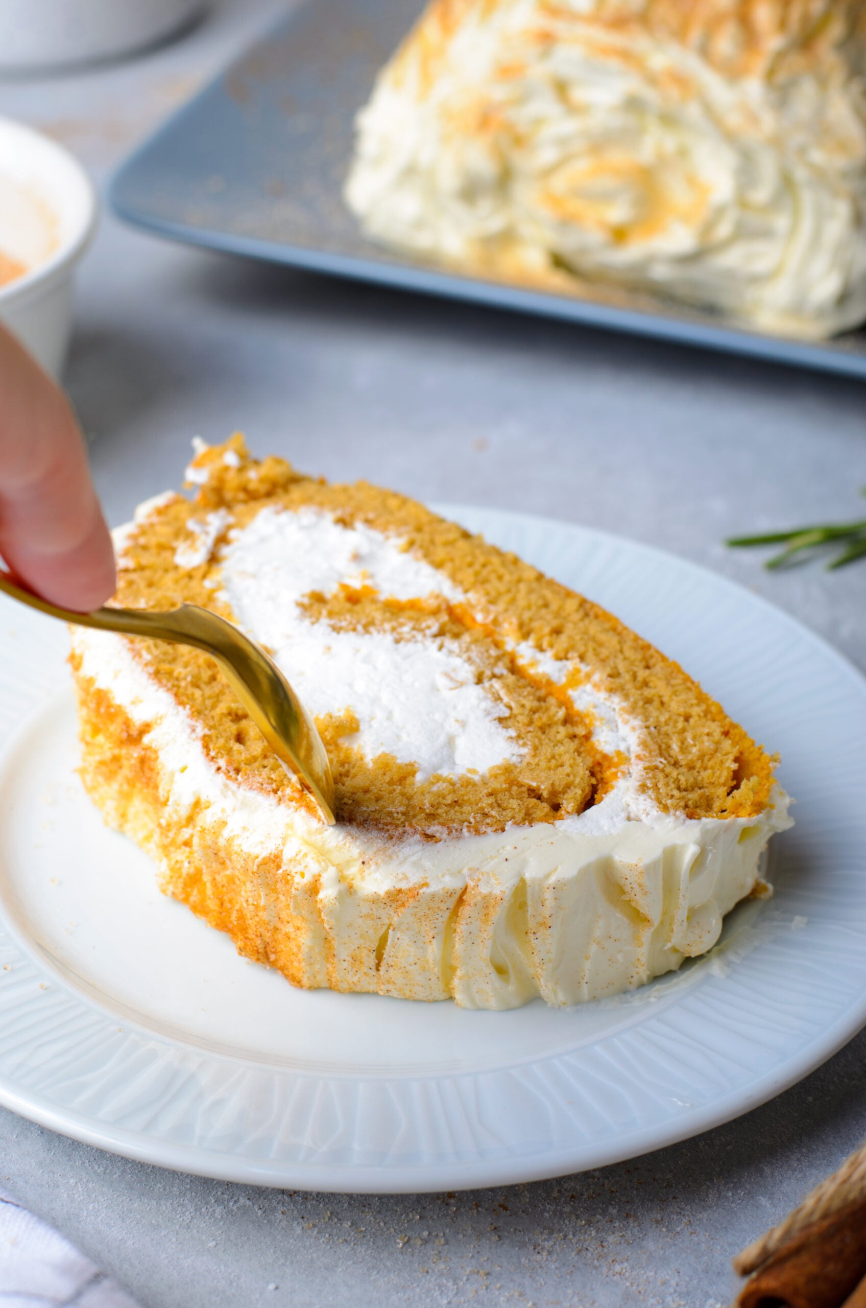Close up view of a gold spoon removing a bite from a slice of GIngerbread Cake Roll.