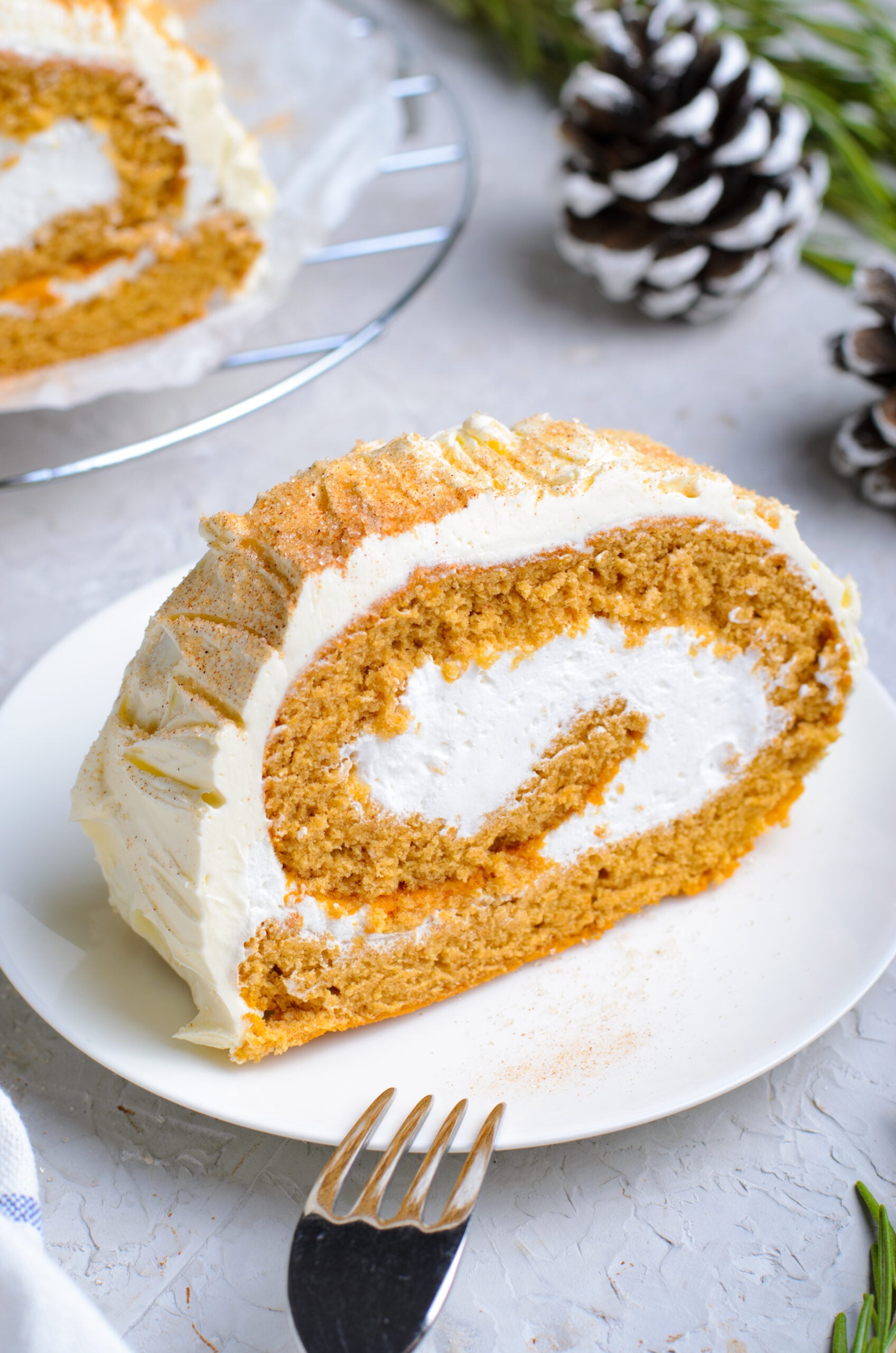 Front view of a slice of GIngerbread Cake Roll on a white plate.