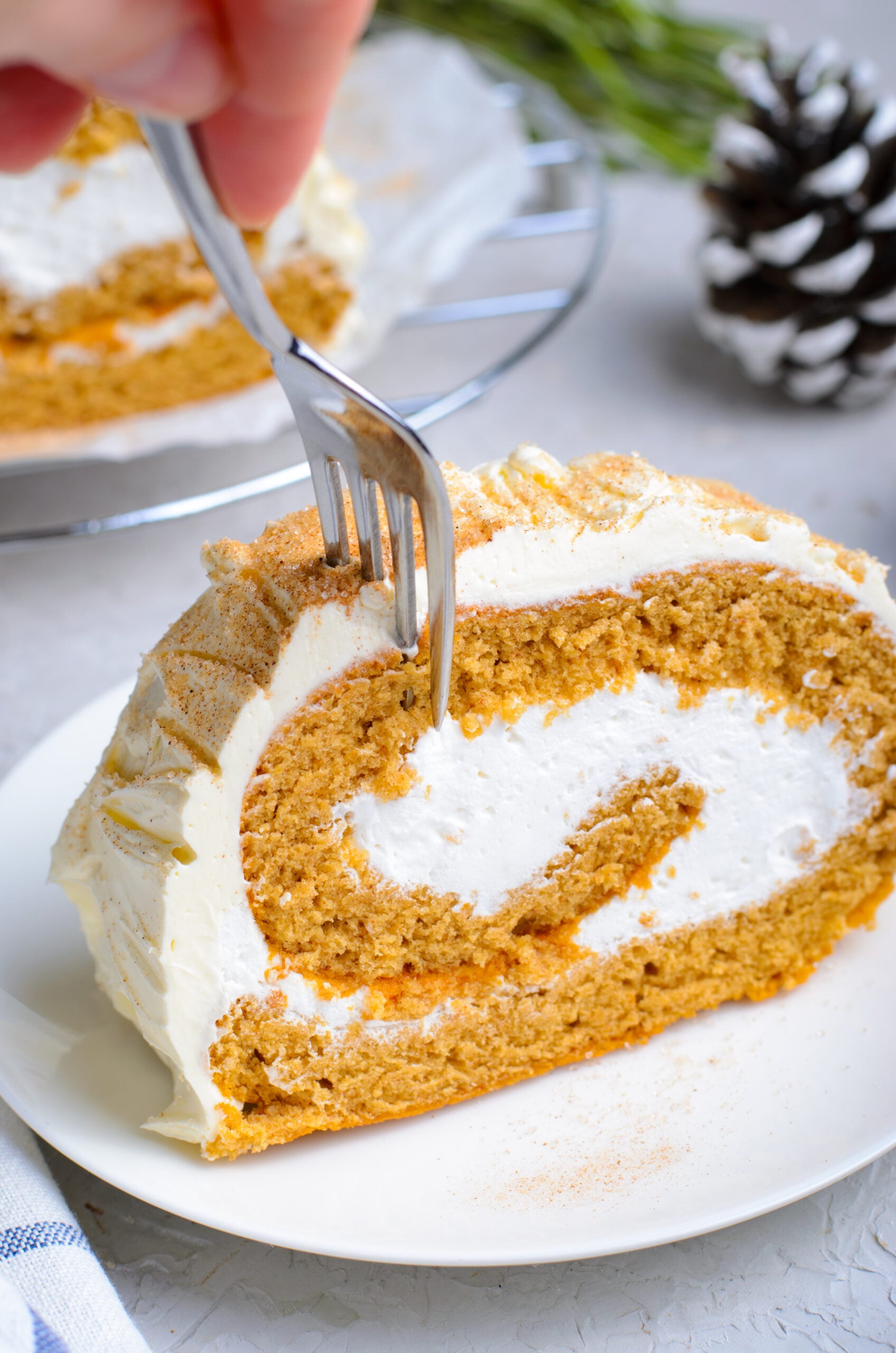 Front view of a silver fork removing a bite from a slice of GIngerbread Cake Roll.