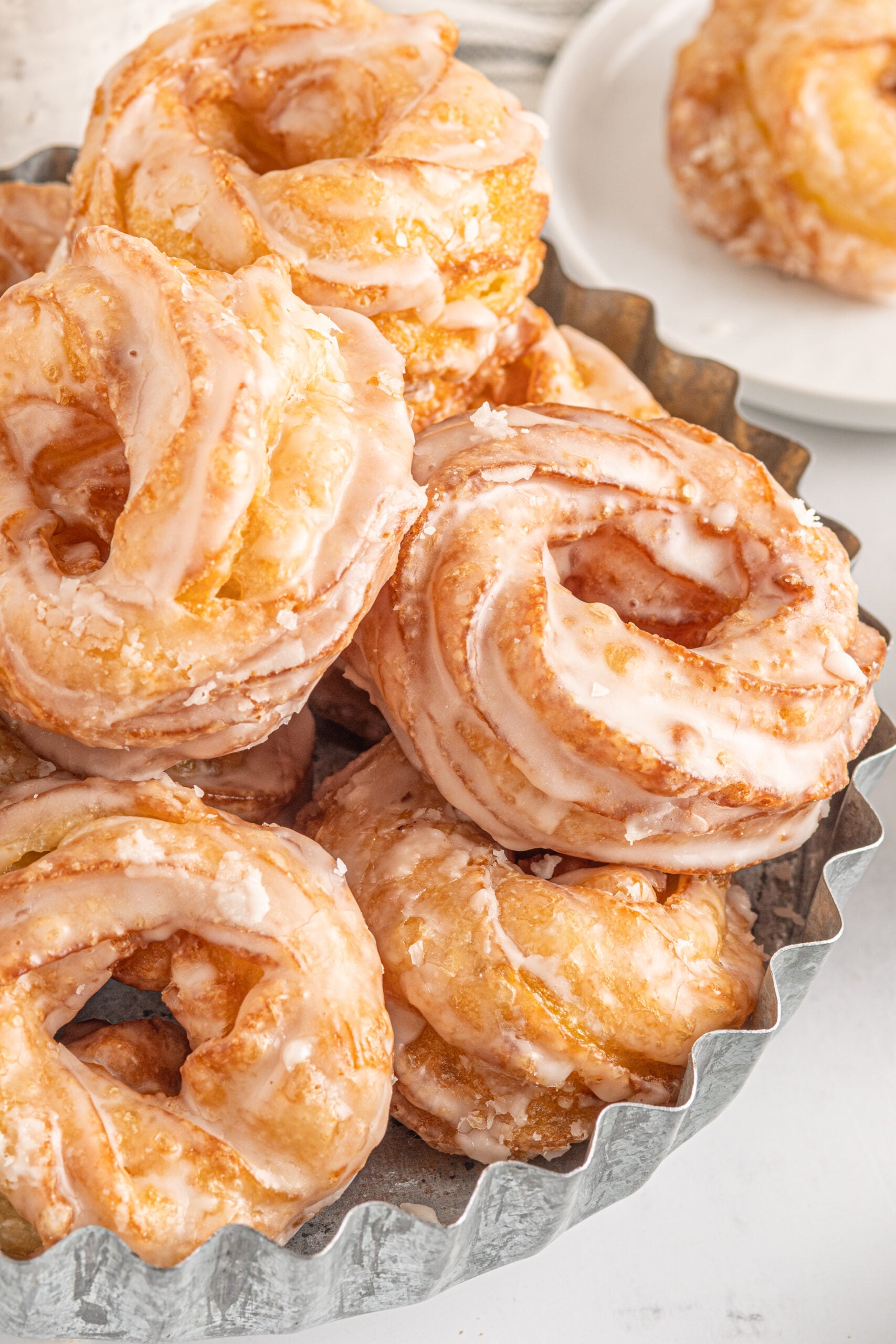 Up close view of French Crullers stacked on a silver serving tray.