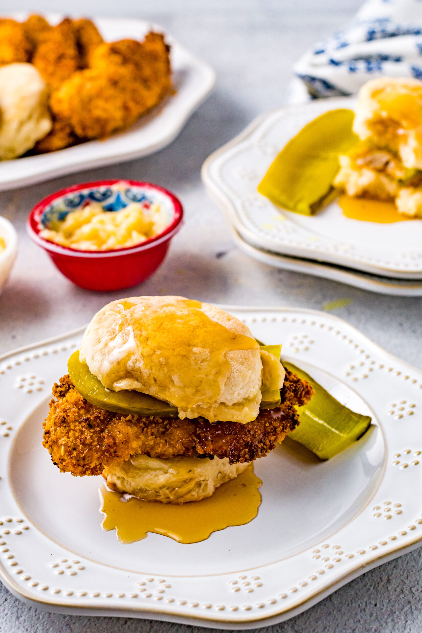 Front view of Honey Butter Chicken Biscuit on a white plate served with two pickle slices.