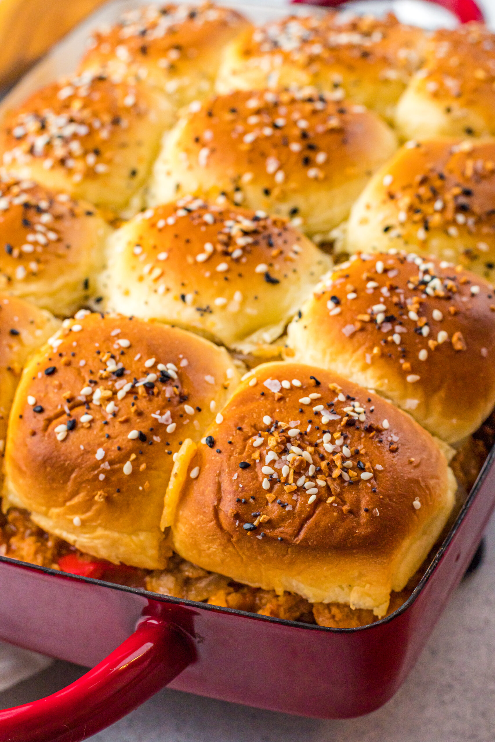 Overhead view of Cheesy Chicken Sloppy Joe Sliders in a red baking dish.