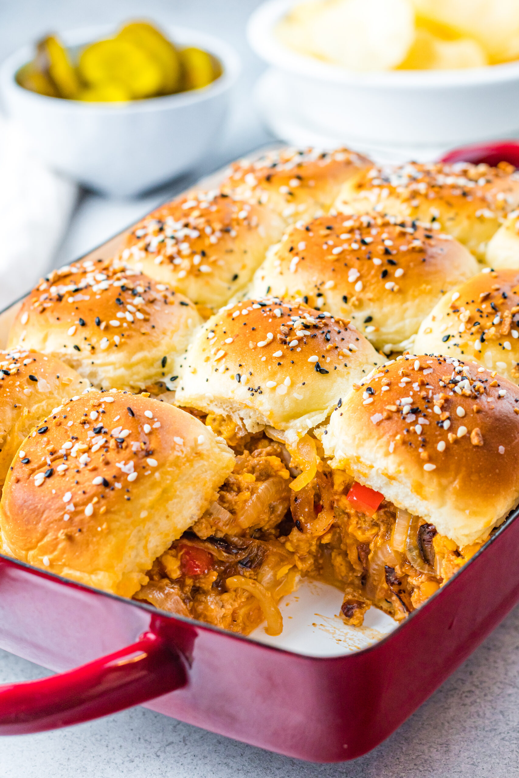 Front view of Cheesy Chicken Sloppy Joe Sliders in a red baking dish.