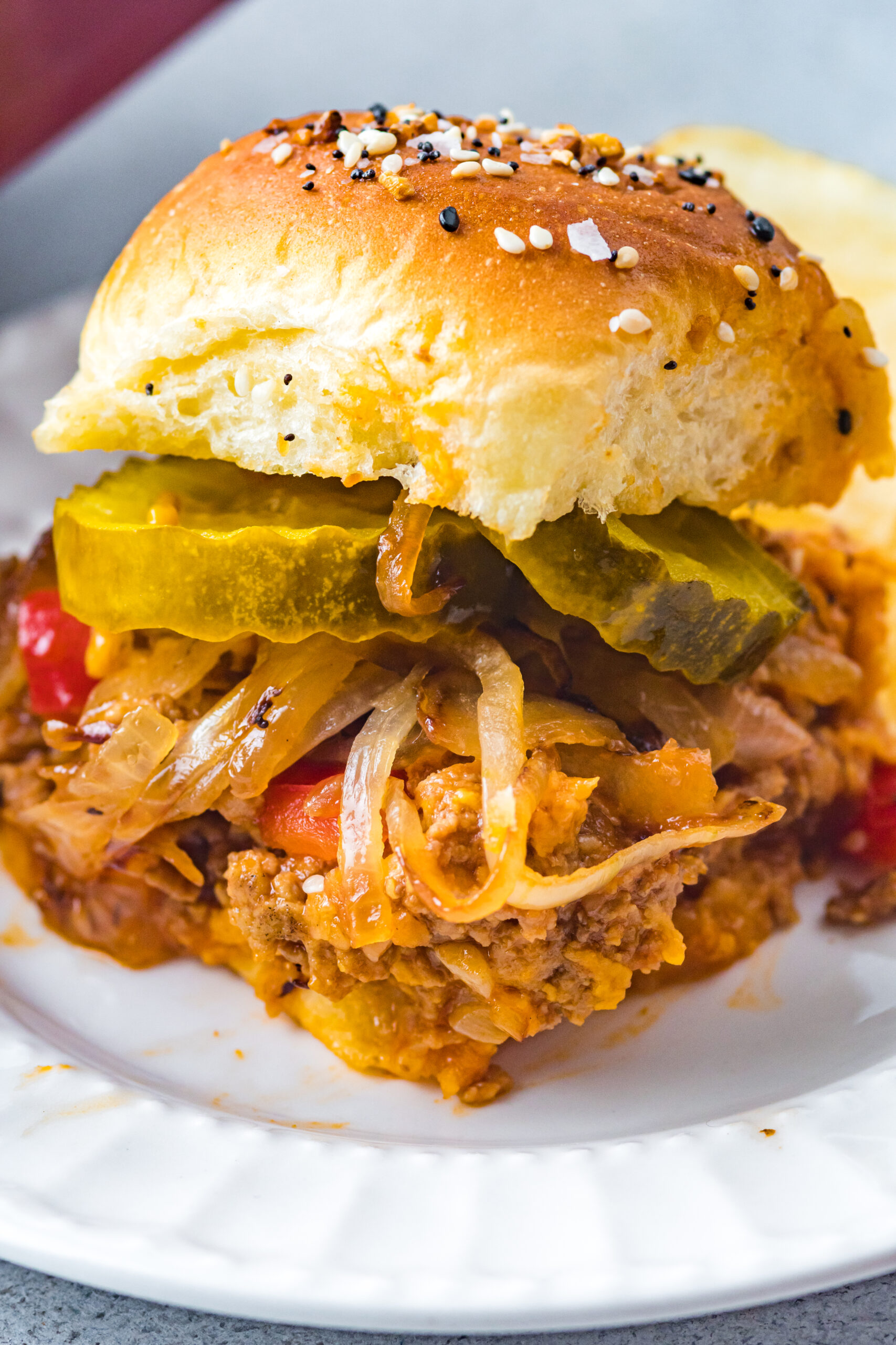 Front view of a Cheesy Chicken Sloppy Joe Slider on a white plate.