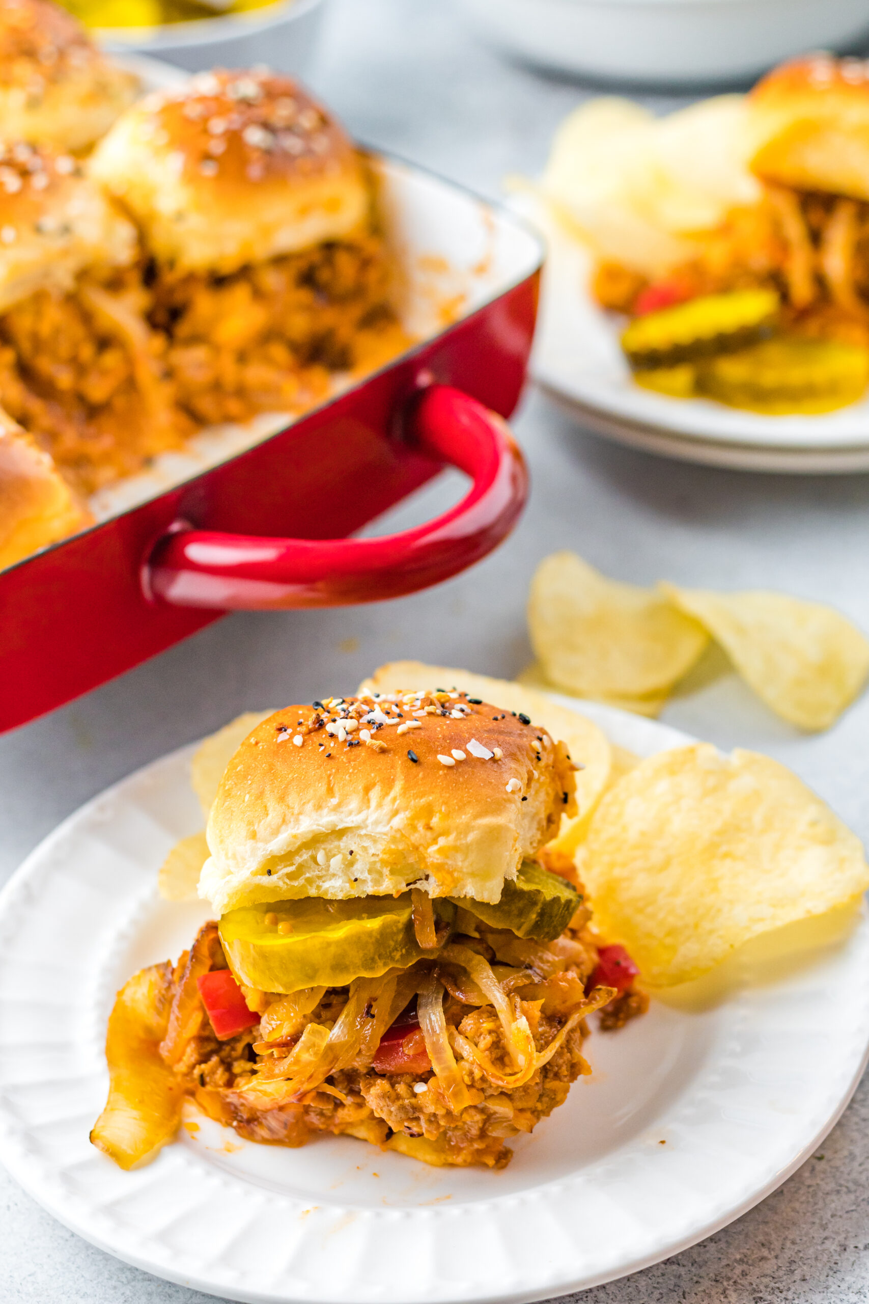 Front view of a Cheesy Chicken Sloppy Joe Slider on a white plate served with chips.