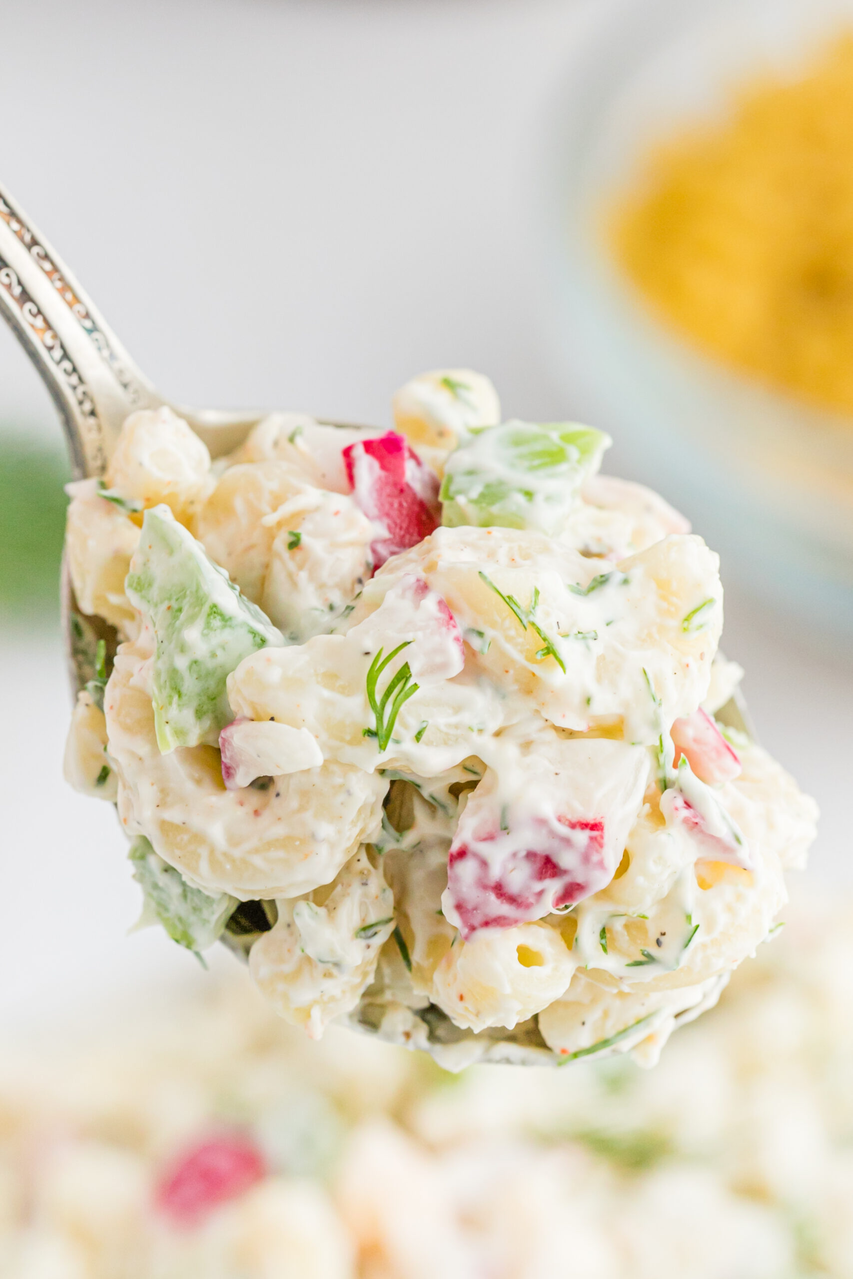 Front view of a bite of Macaroni Dill Pasta Salad on a silver spoon.