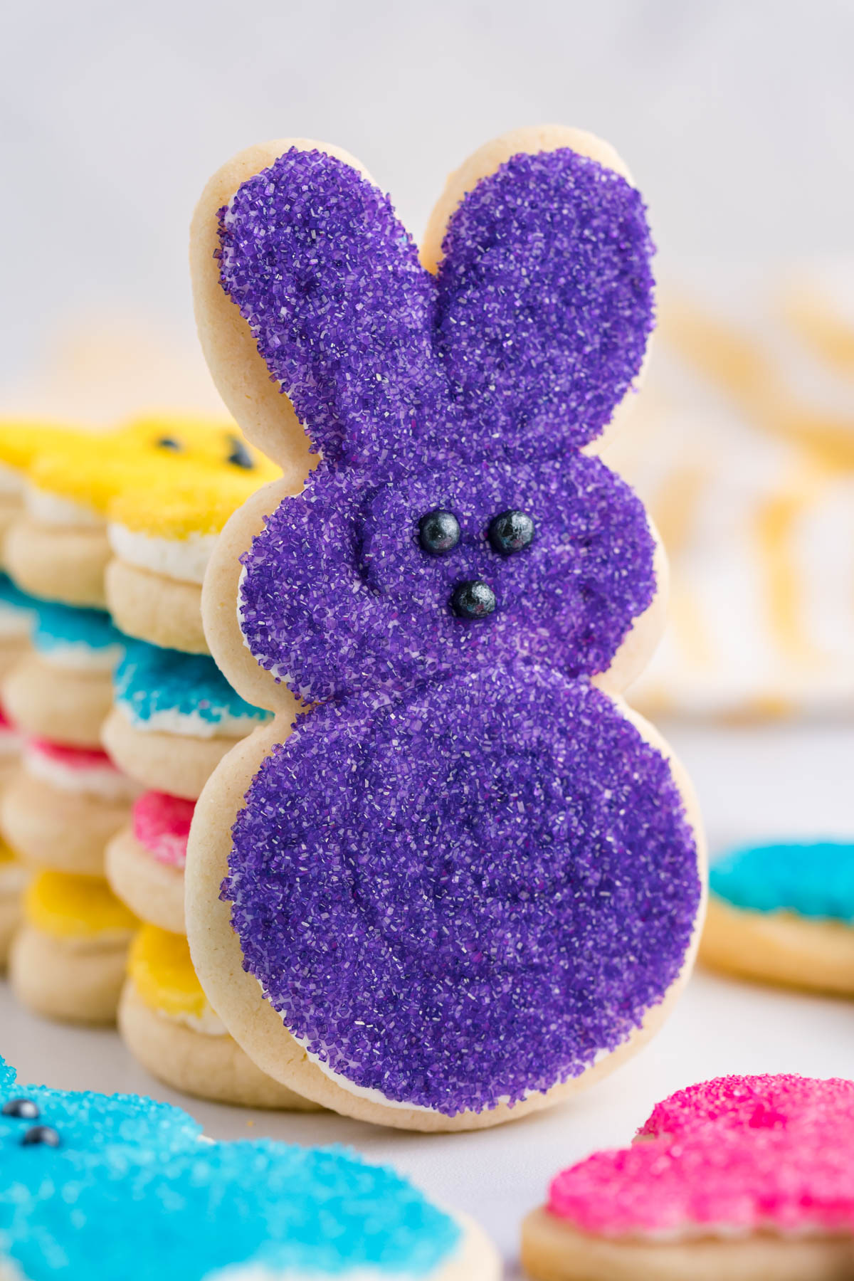 A purple Bunny Cookie propped up against a stack of multicolored Easter Bunny Cookies.