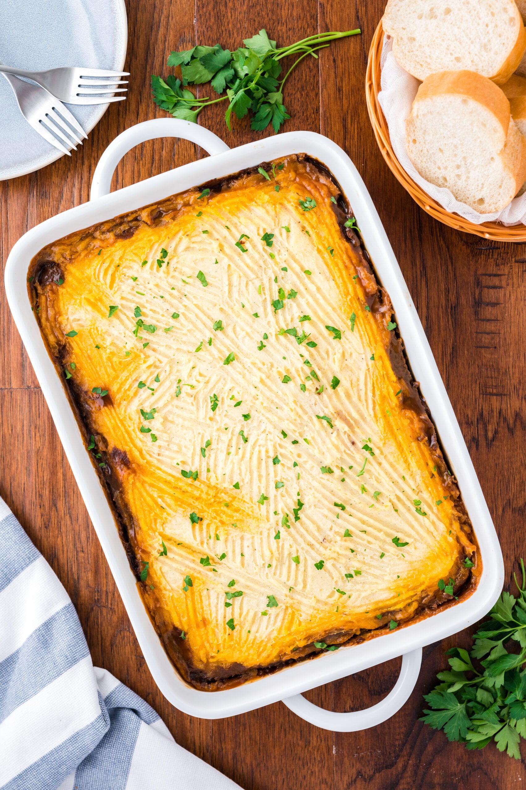 Overhead shot of the baked Shepherd's Pie in a white baking dish topped with chopped parsley.