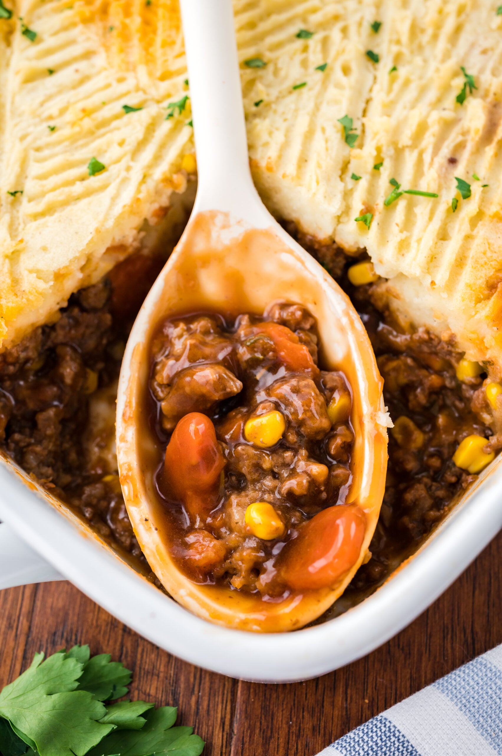 A large spoon removing Shepherd's Pie from the baking dish.