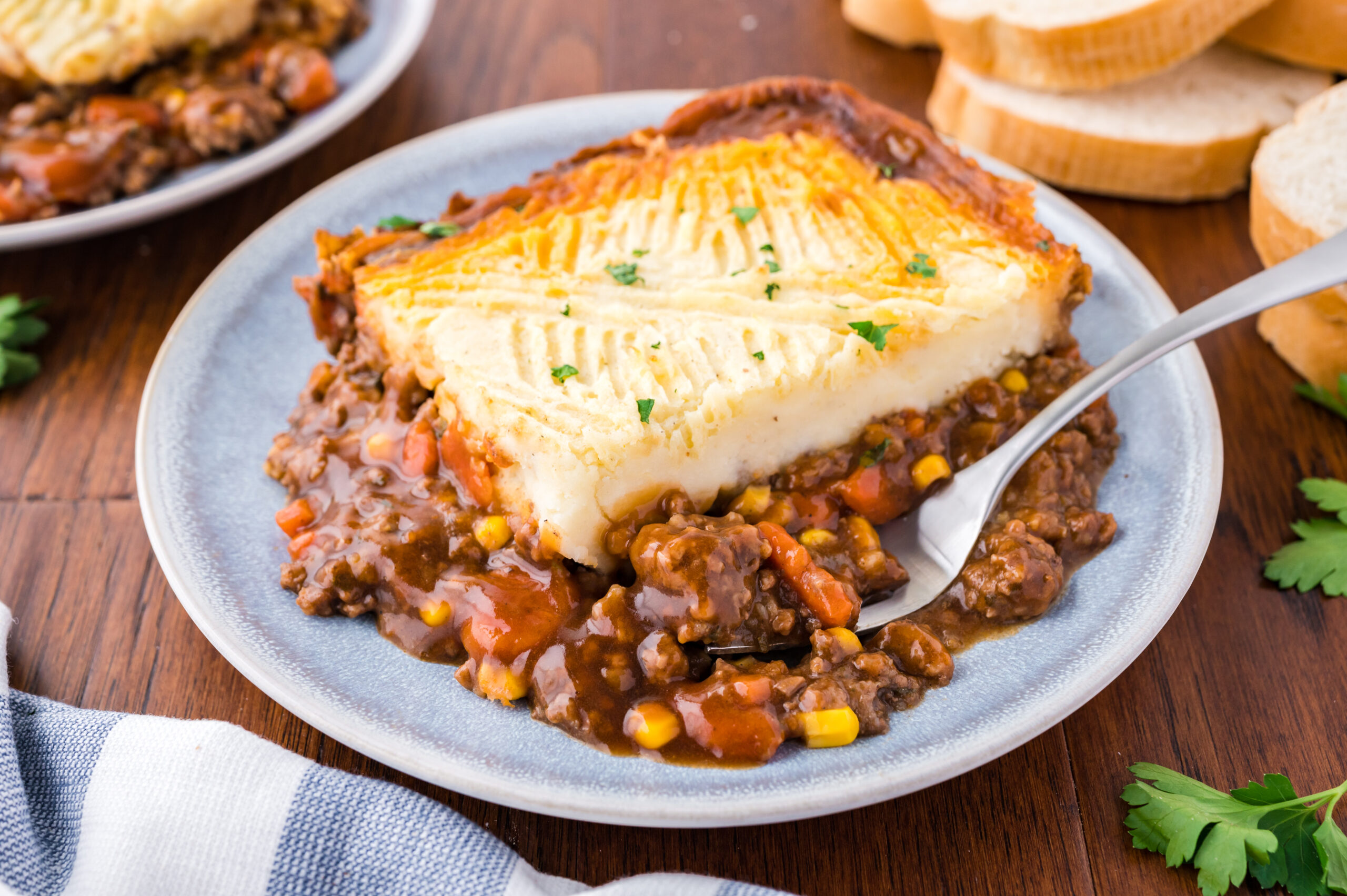 Shepherd's pie on a gray and white plate with a silver fork.