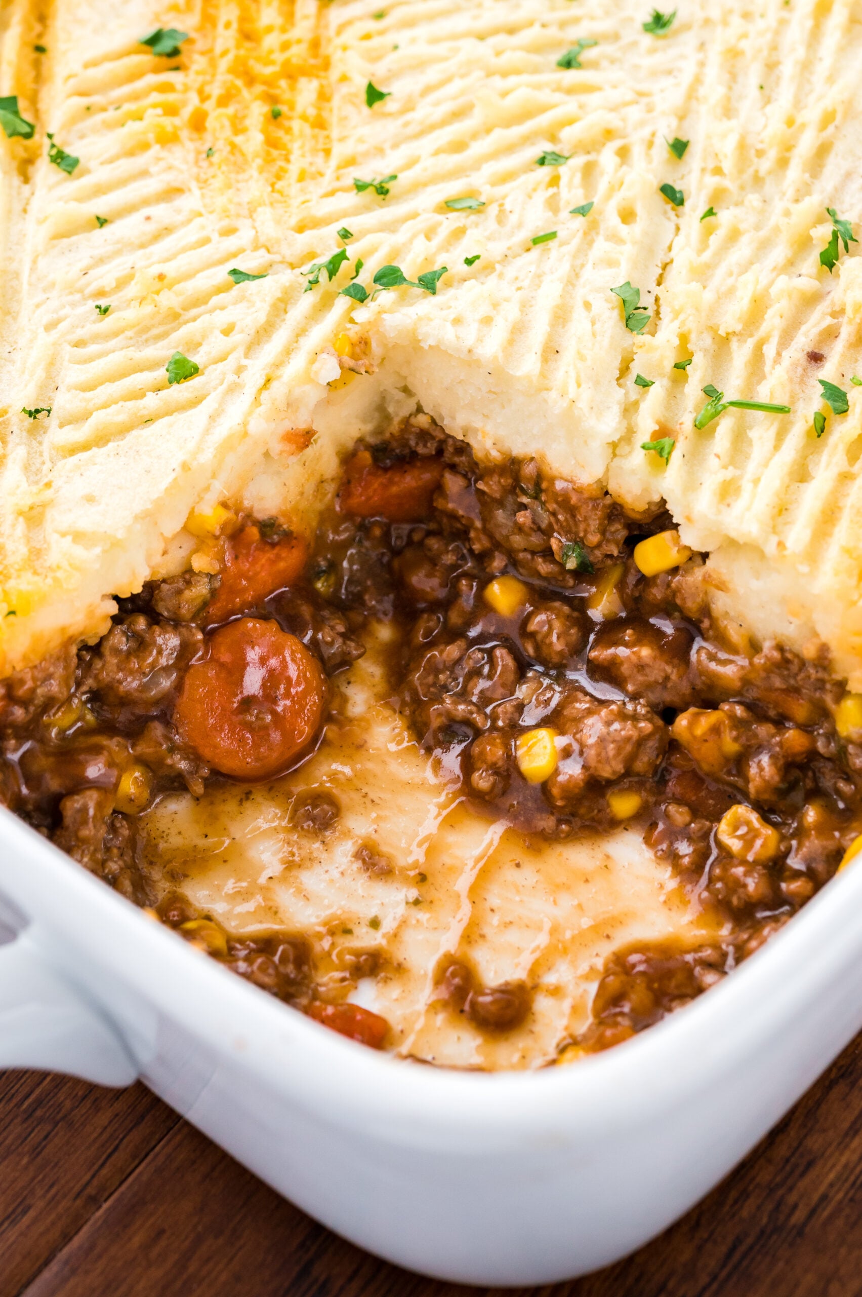 Close up of the Shepherds pie in a white casserole baking dish with a slice removed