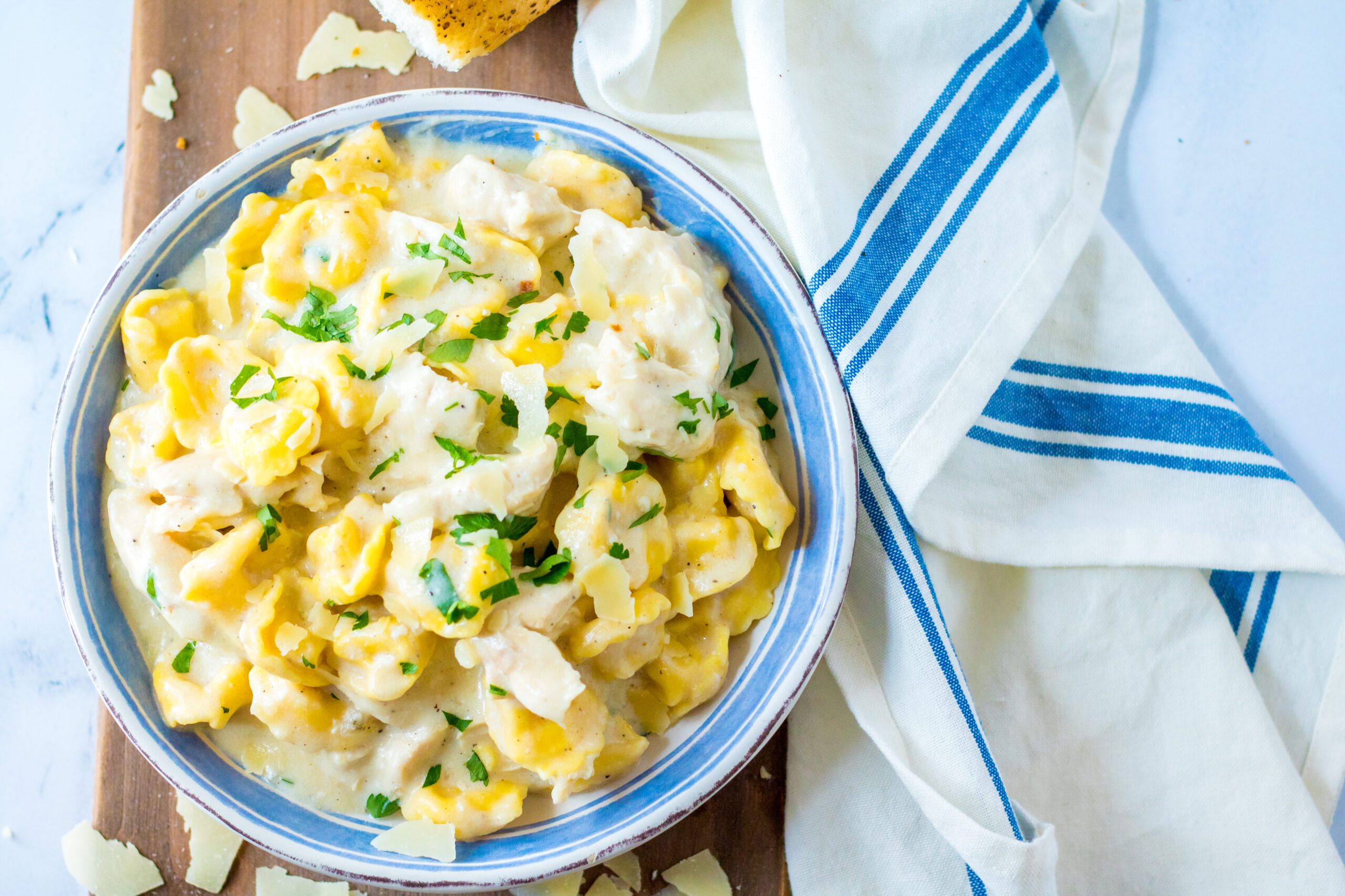 Overhead view of Slow Cooker Chicken Tortellini in a white and blue bowl.