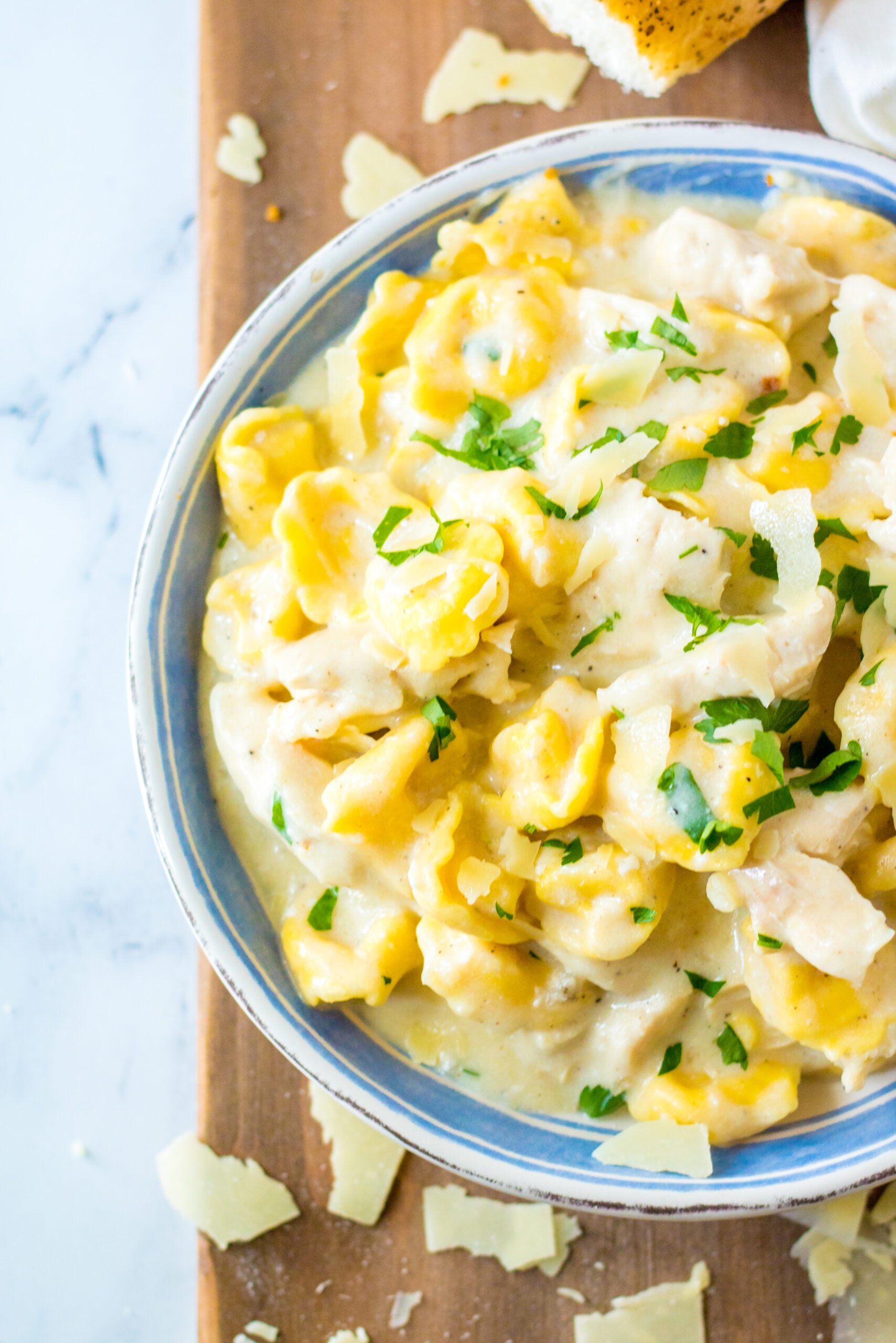 Close up view of Slow Cooker Chicken Tortellini in a white and blue bowl.