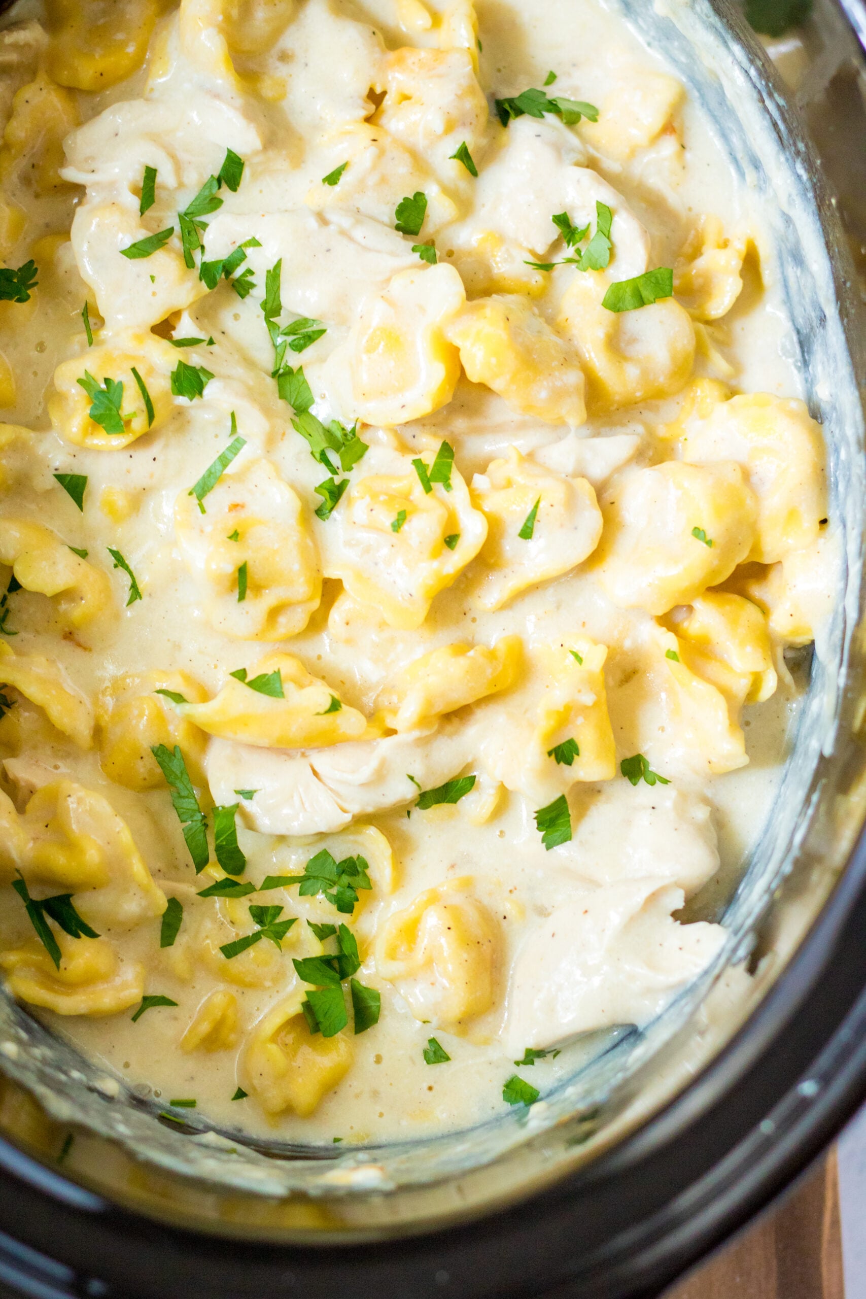 Close up view of Slow Cooker Chicken Tortellini in a crock pot.
