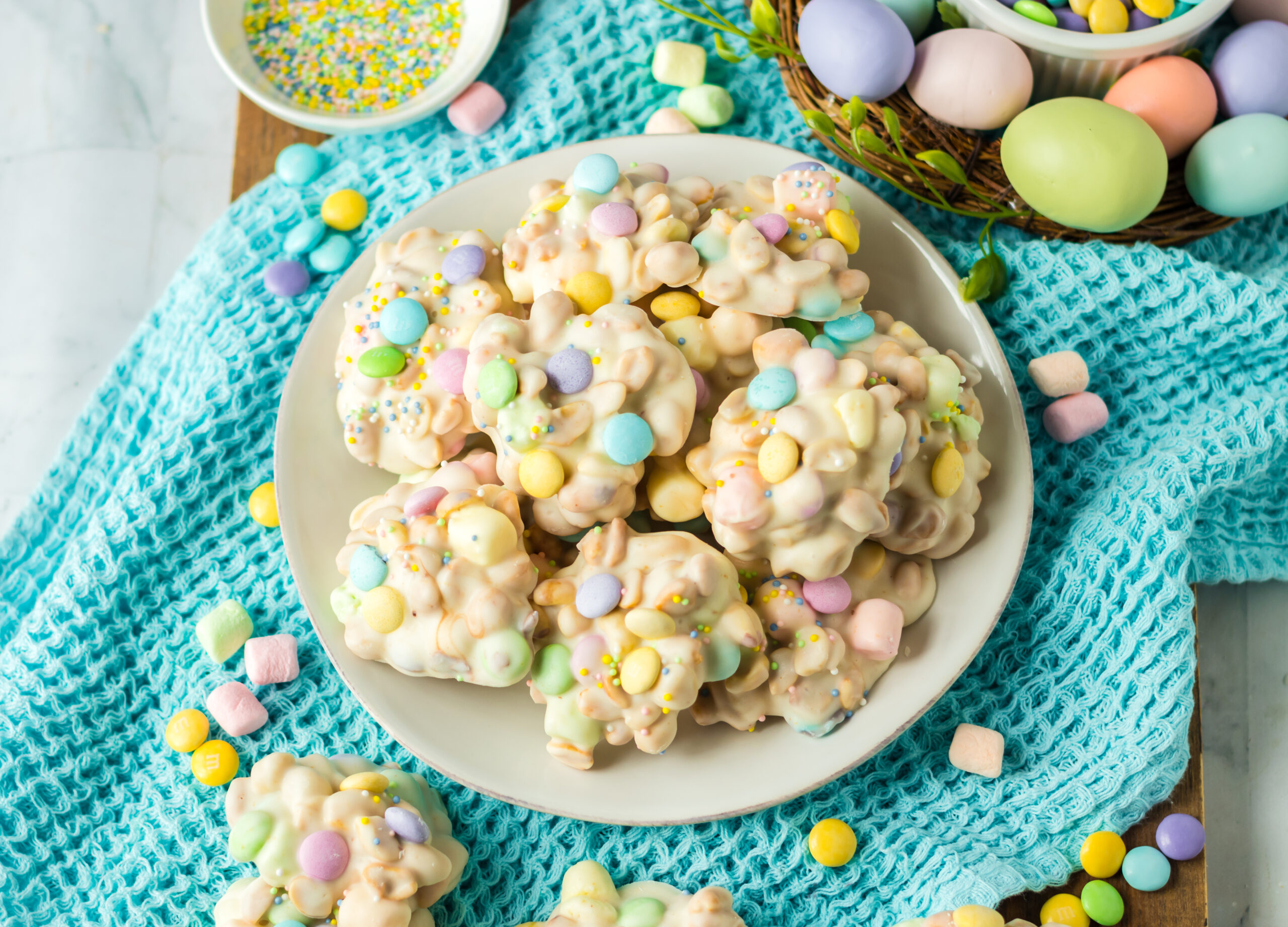 Overhead view of the slow cooker Easter candy on a white plate on a teal linen.