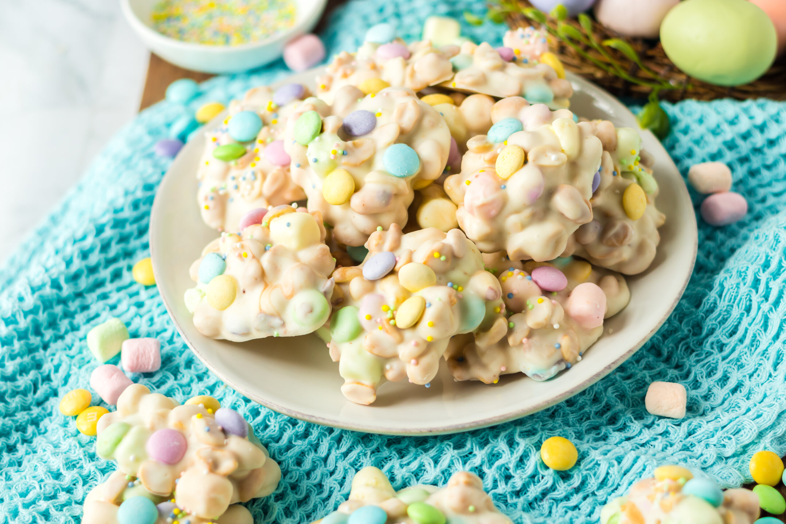 Side view of the stacked candy on a white plate on a teal colored linen.