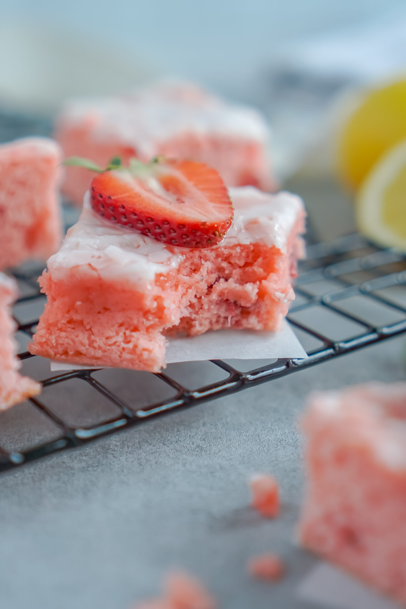 Front view of a Strawberry Lemon Brownie on a black wire rack with a bite removed.