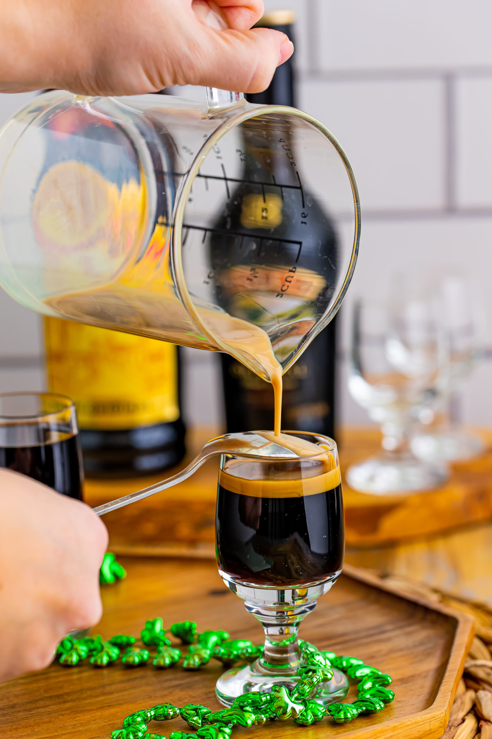 Pouring the Bailey's Irish cream over a spoon into the shot glass. 
