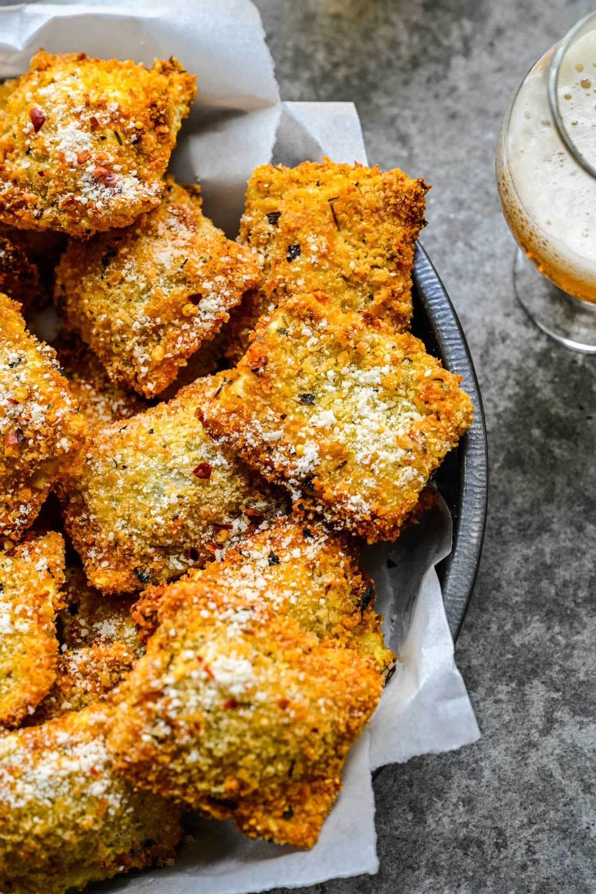 Close up view of Air Fryer Ravioli in a black serving tray with parchment paper.