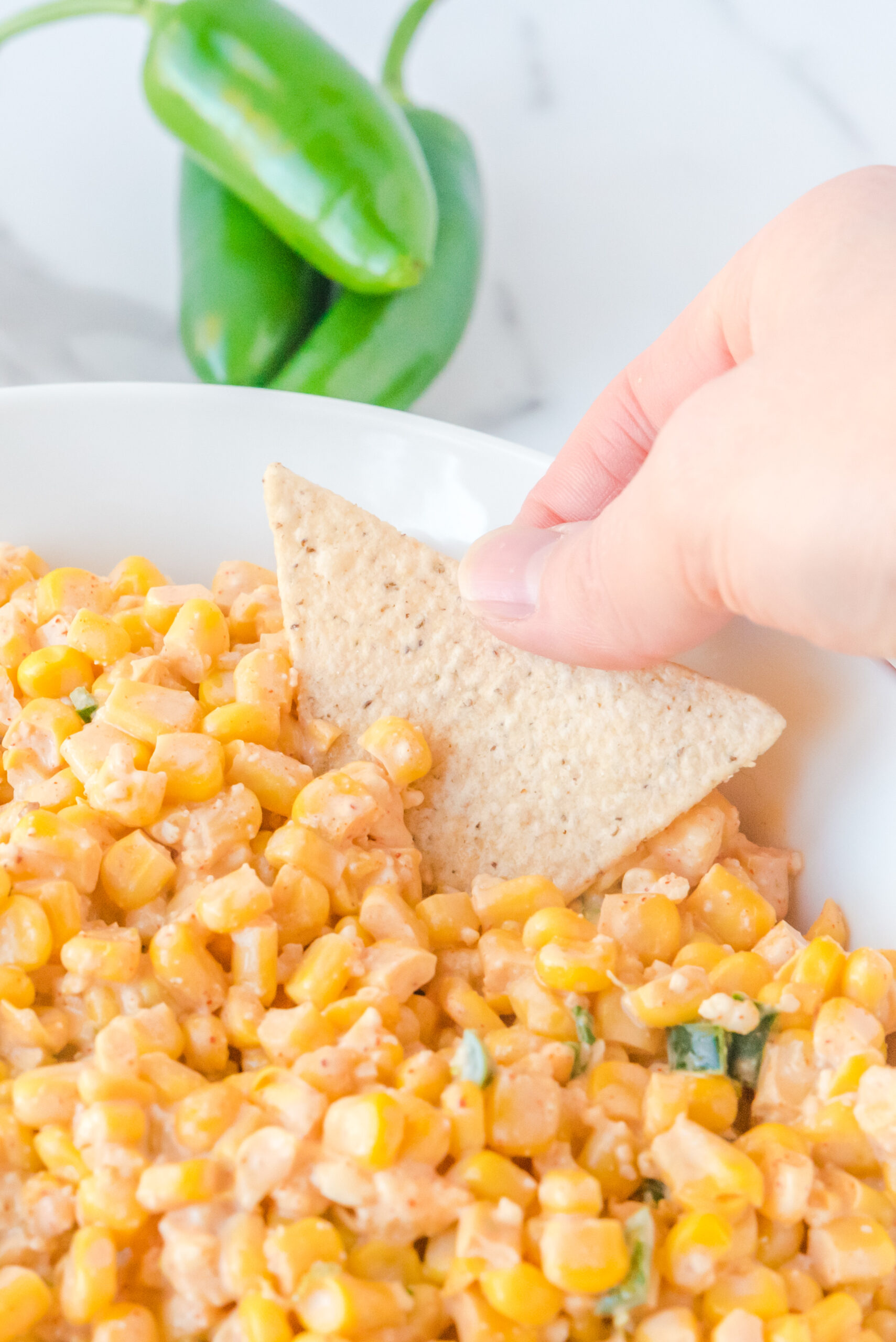 A chip being dipped into Mexican Street Corn Salad.
