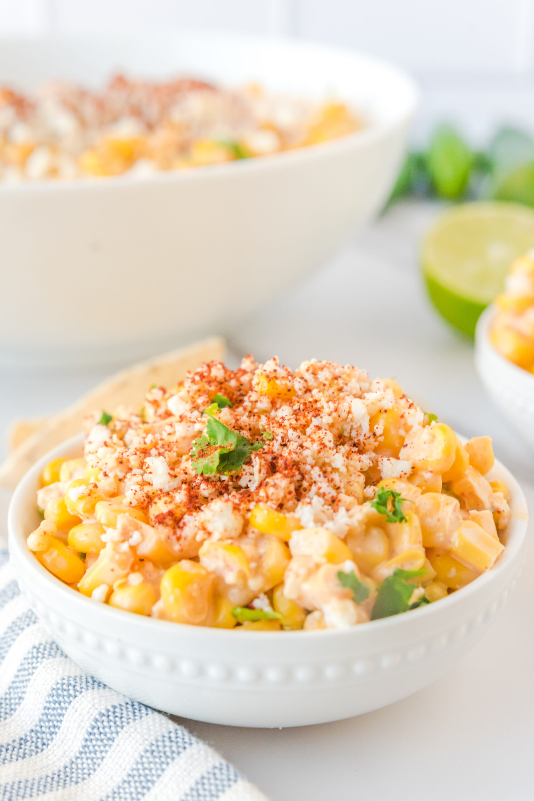 Mexican Street Corn Salad in a white bowl topped with paprika and fresh queso fresco.