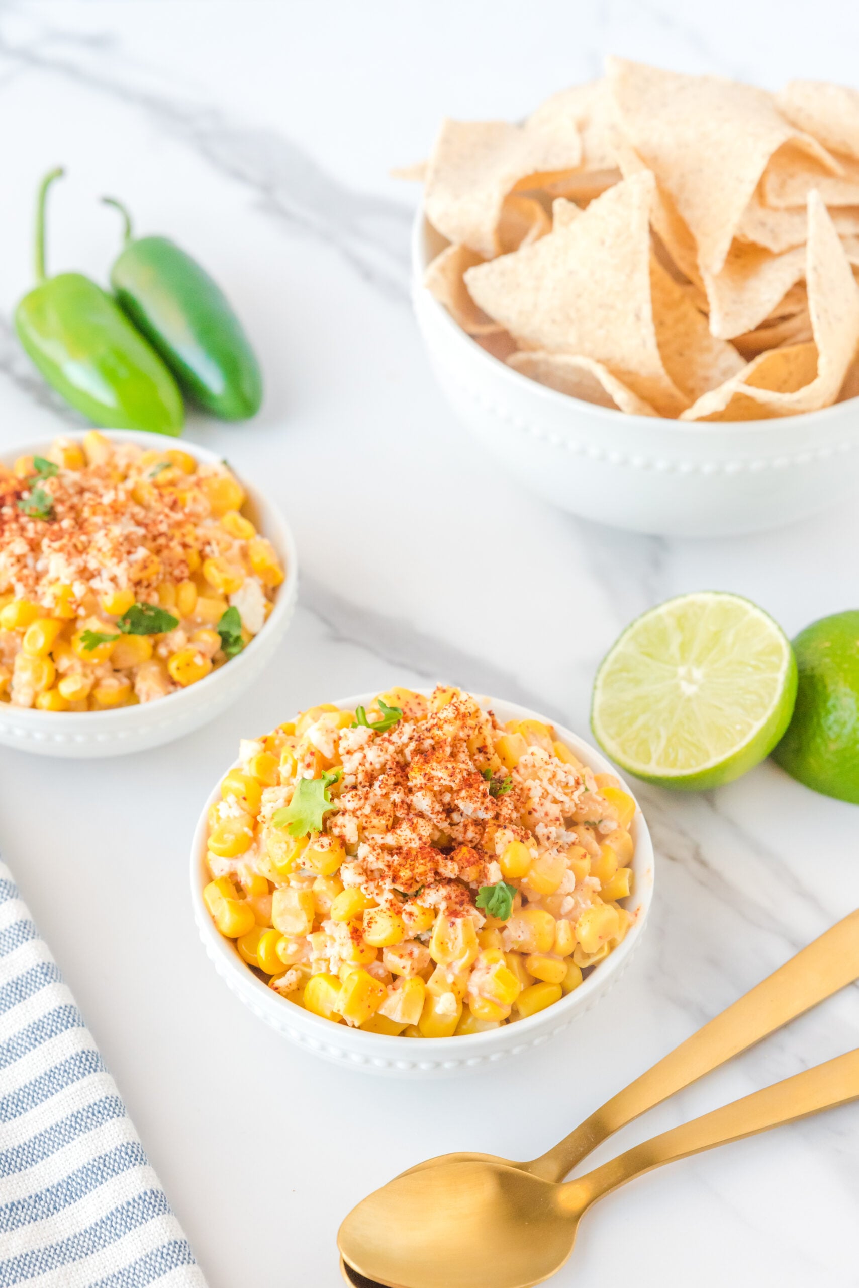 Mexican Street Corn Salad in two white bowls topped with paprika and fresh queso fresco.