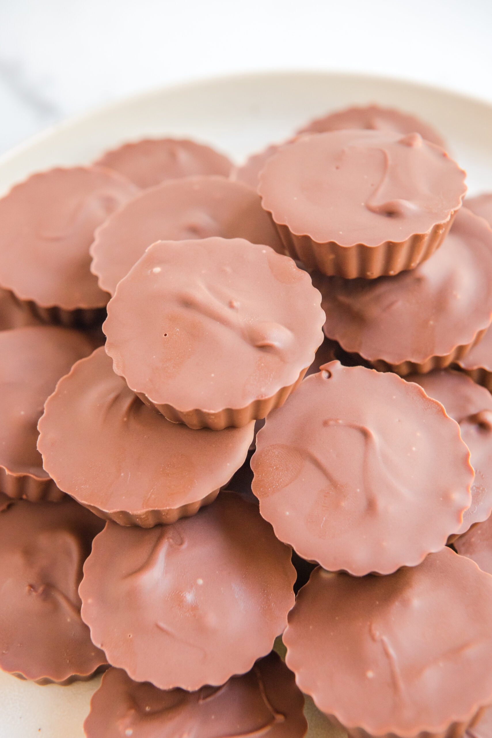 Homemade Reese's Peanut Butter Cups stacked on a white serving plate.