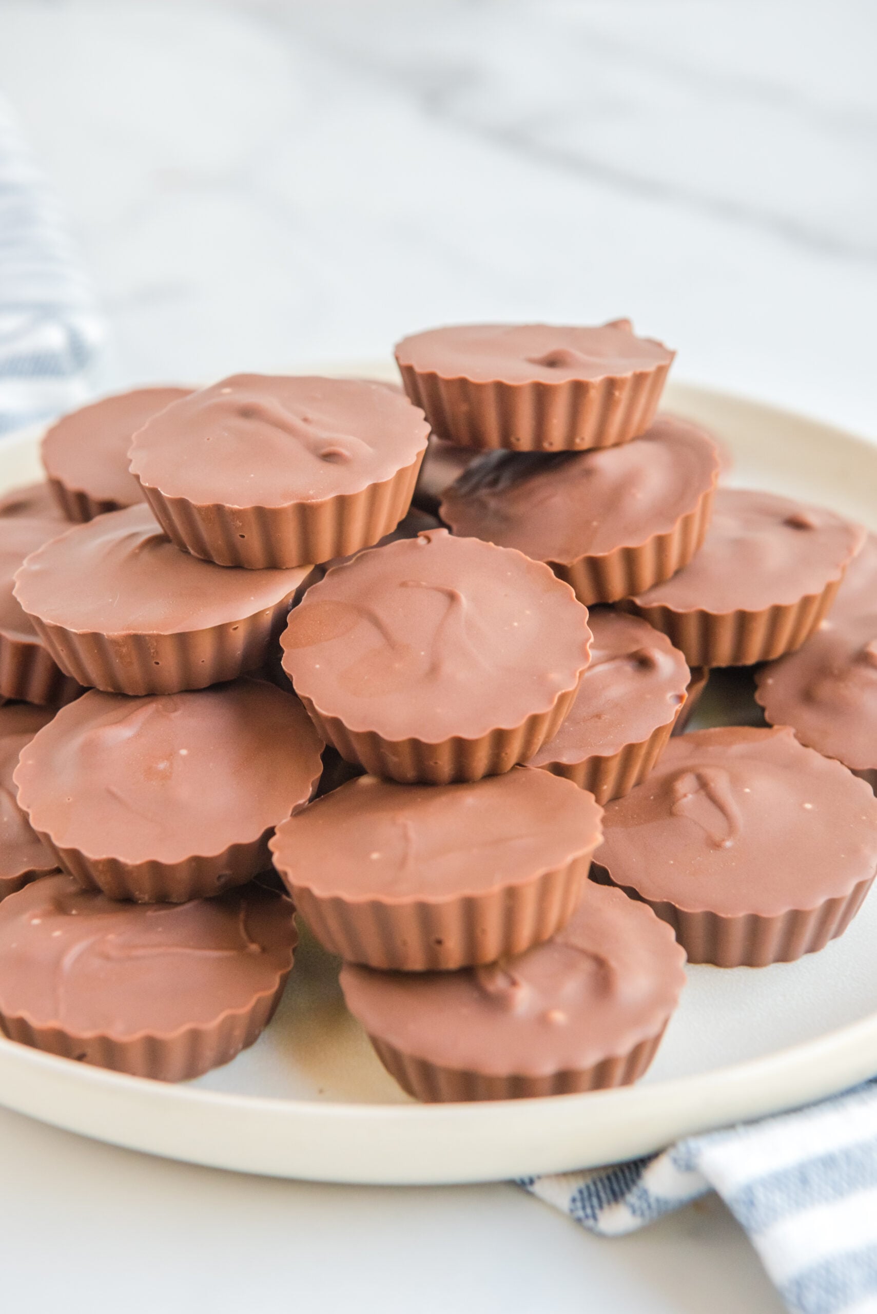 Homemade Reese's Peanut Butter Cups stacked on a white serving plate.