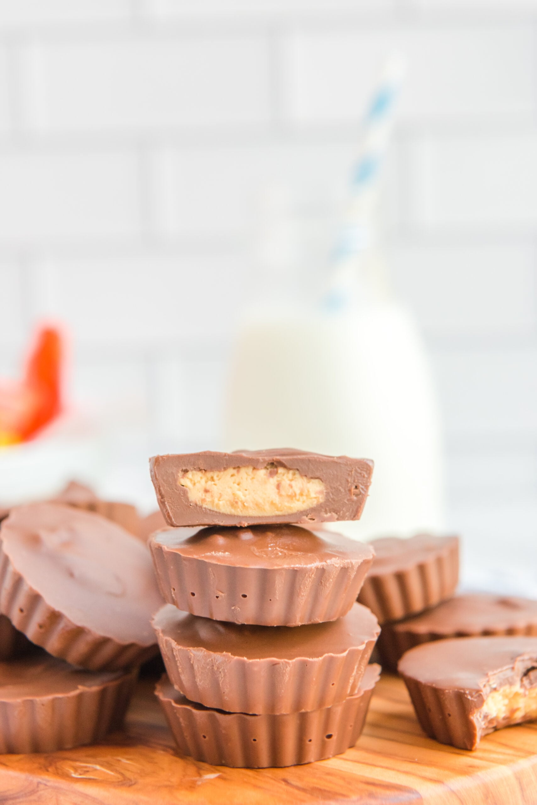 Four Homemade Reese's Peanut Butter Cups stacked on a wooden serving board with a bite removed from one to show the filling.